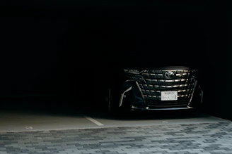 A dark luxury car parked in a dimly lit garage.