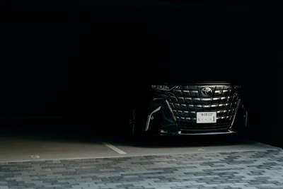 A dark luxury car parked in a dimly lit garage.