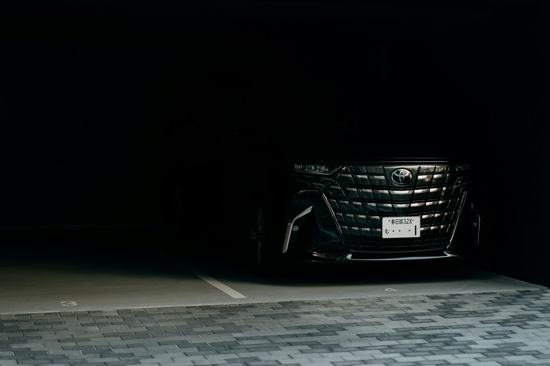 A dark luxury car parked in a dimly lit garage.