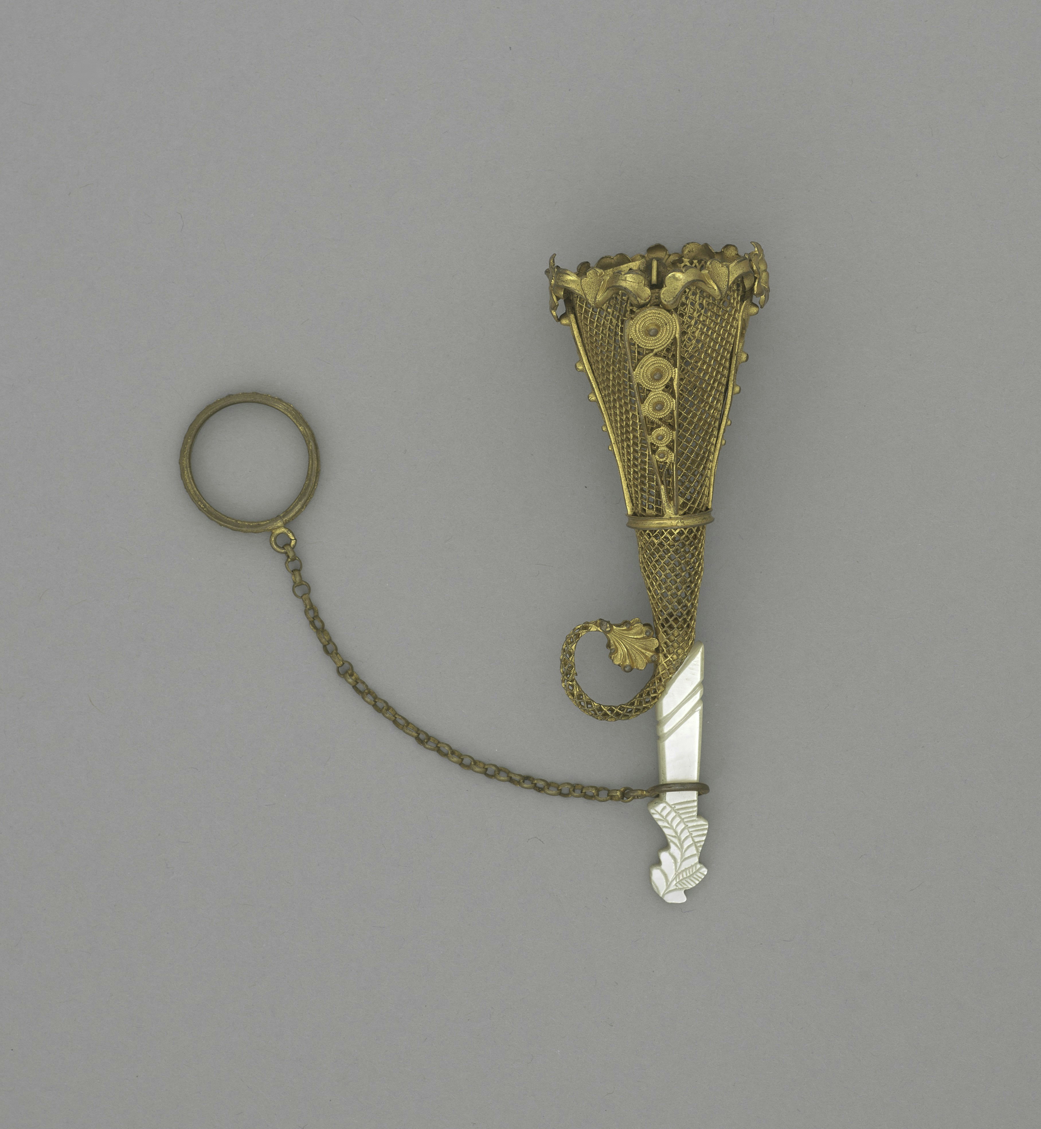 Un colgante decorativo en forma de abanico dorado y plata con un anillo.