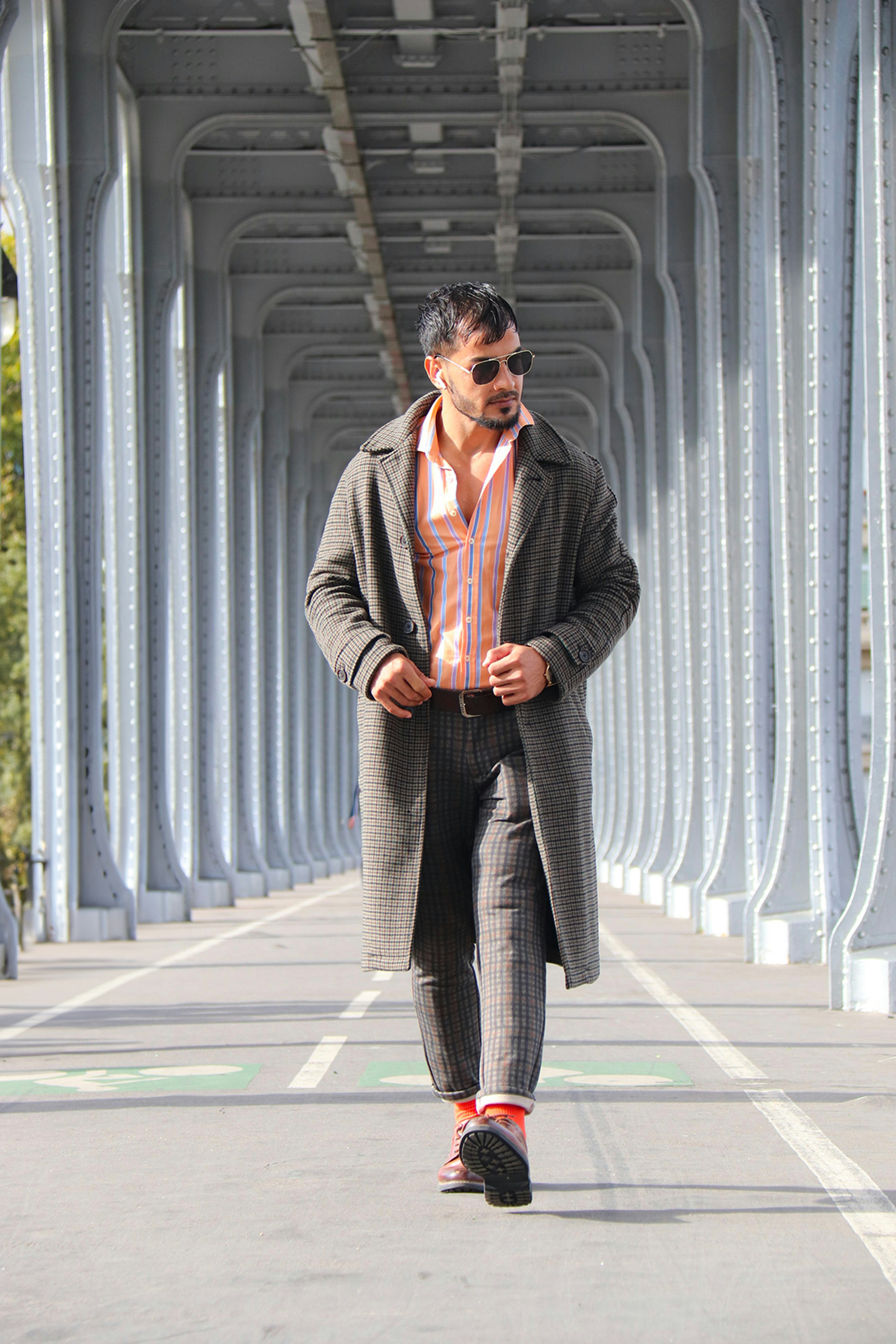 Man in stylish coat walking on a bridge