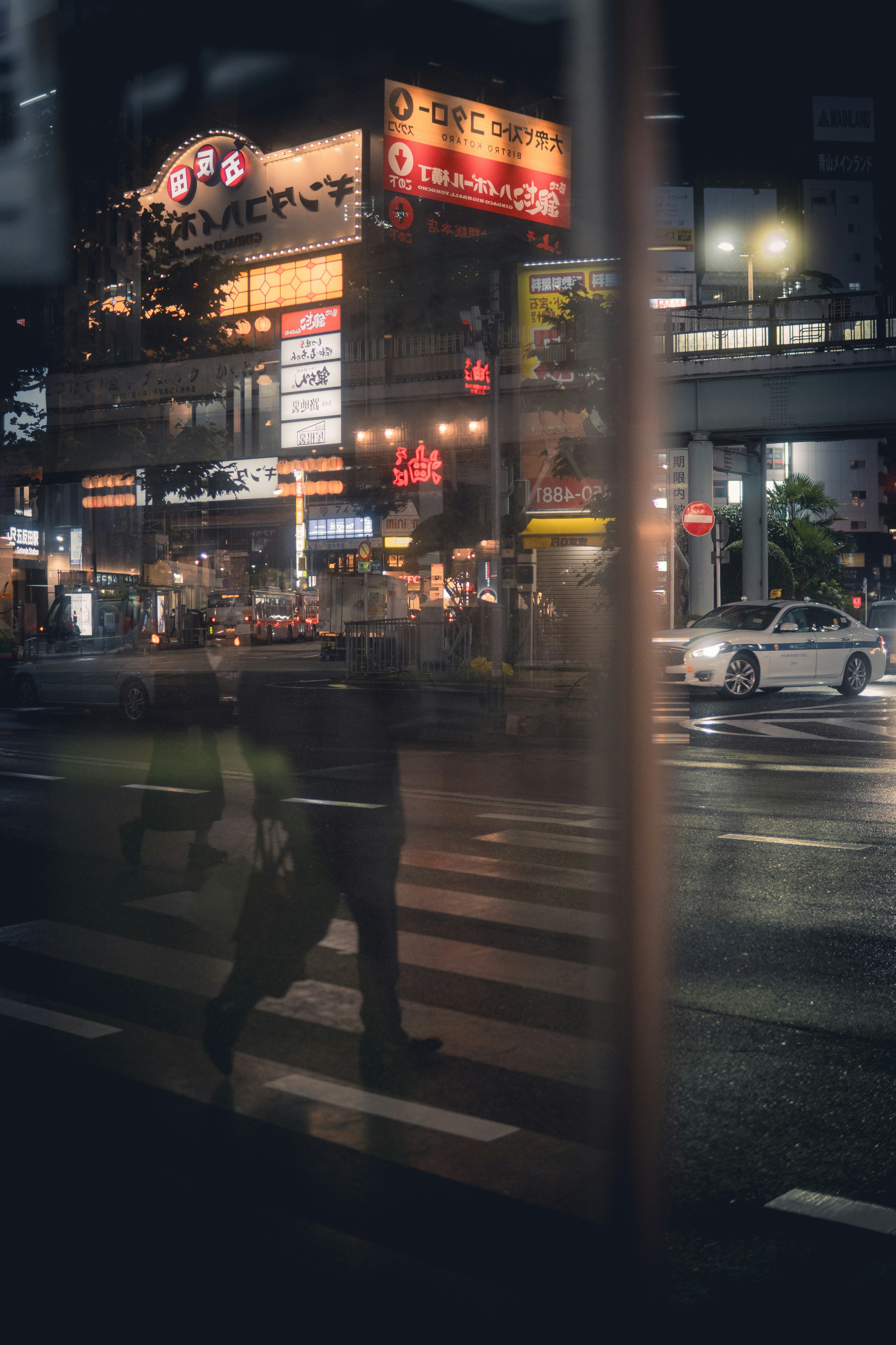 Uma pessoa atravessa uma rua à noite em uma cidade.