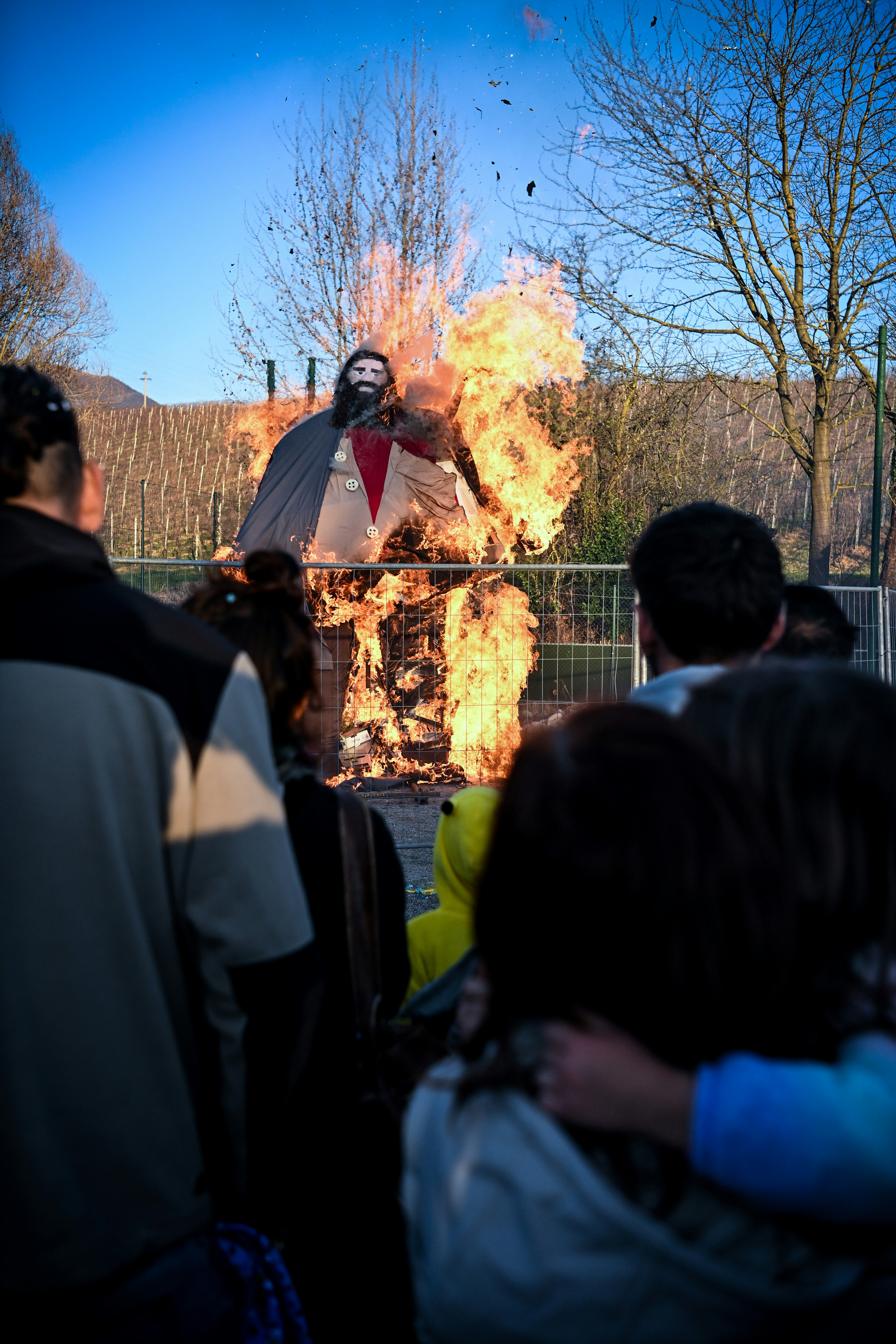 Una figura arde en una pira vigilada por una multitud