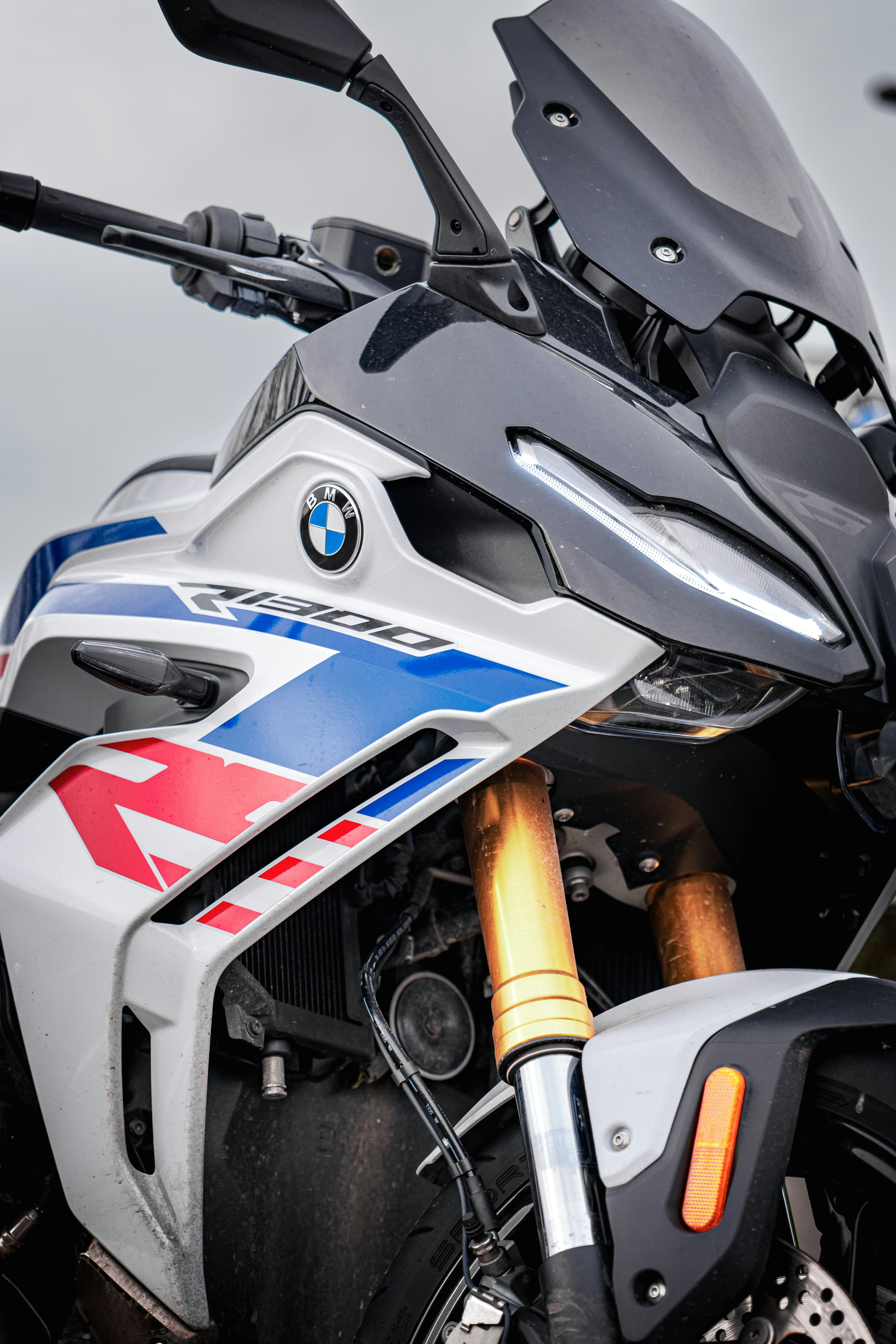 Uma moto BMW branca e azul com garfos dourados.