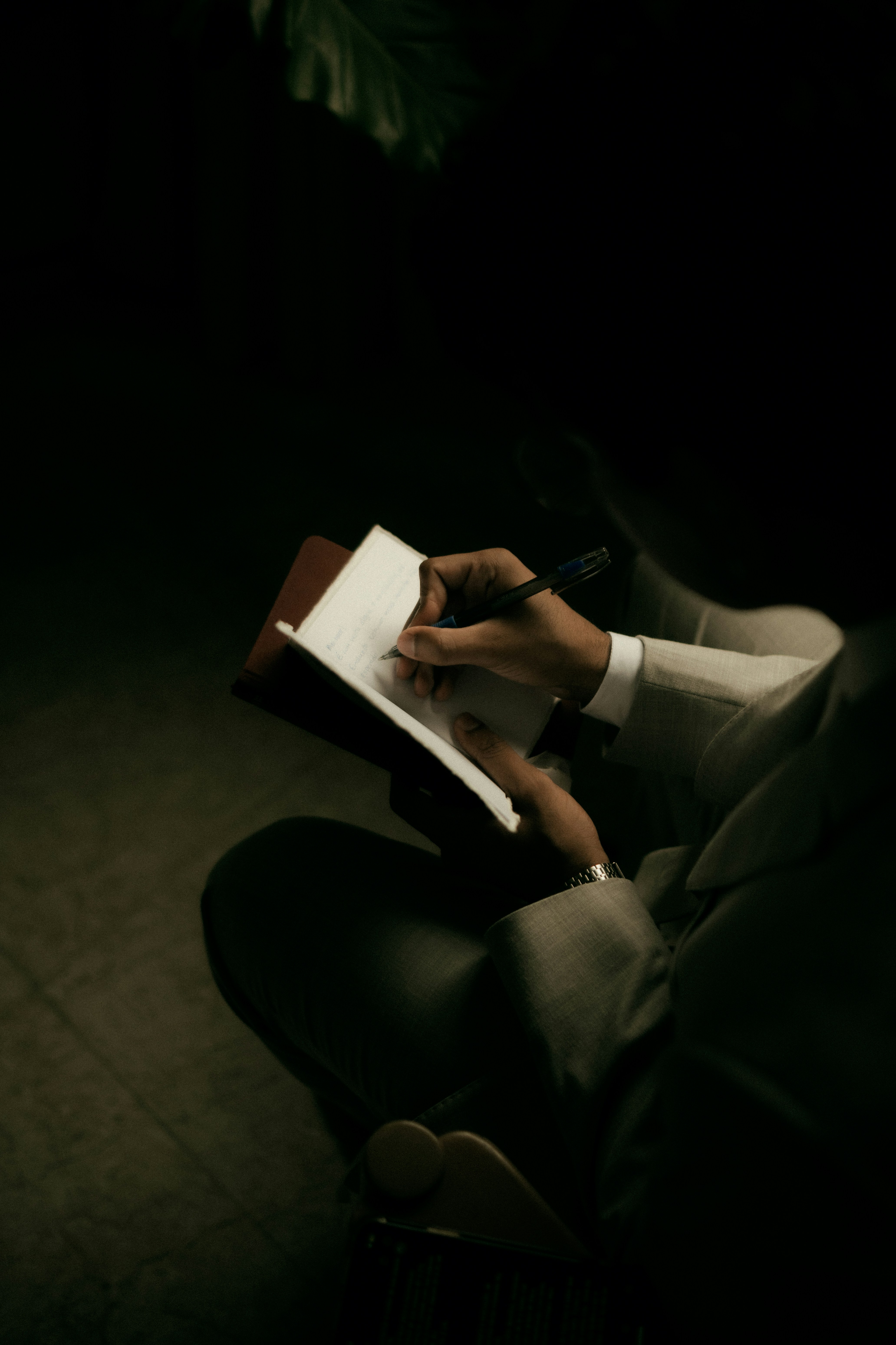 Person writing in a notebook with a pen.