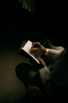 Person writing in a notebook with a pen.