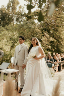 A wedding ceremony outdoors with a couple holding hands.