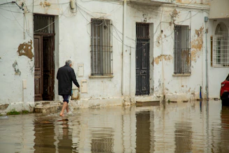 Man walks through flooded street in front of old buildings