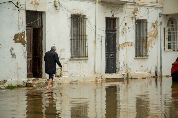 Man walks through flooded street in front of old buildings