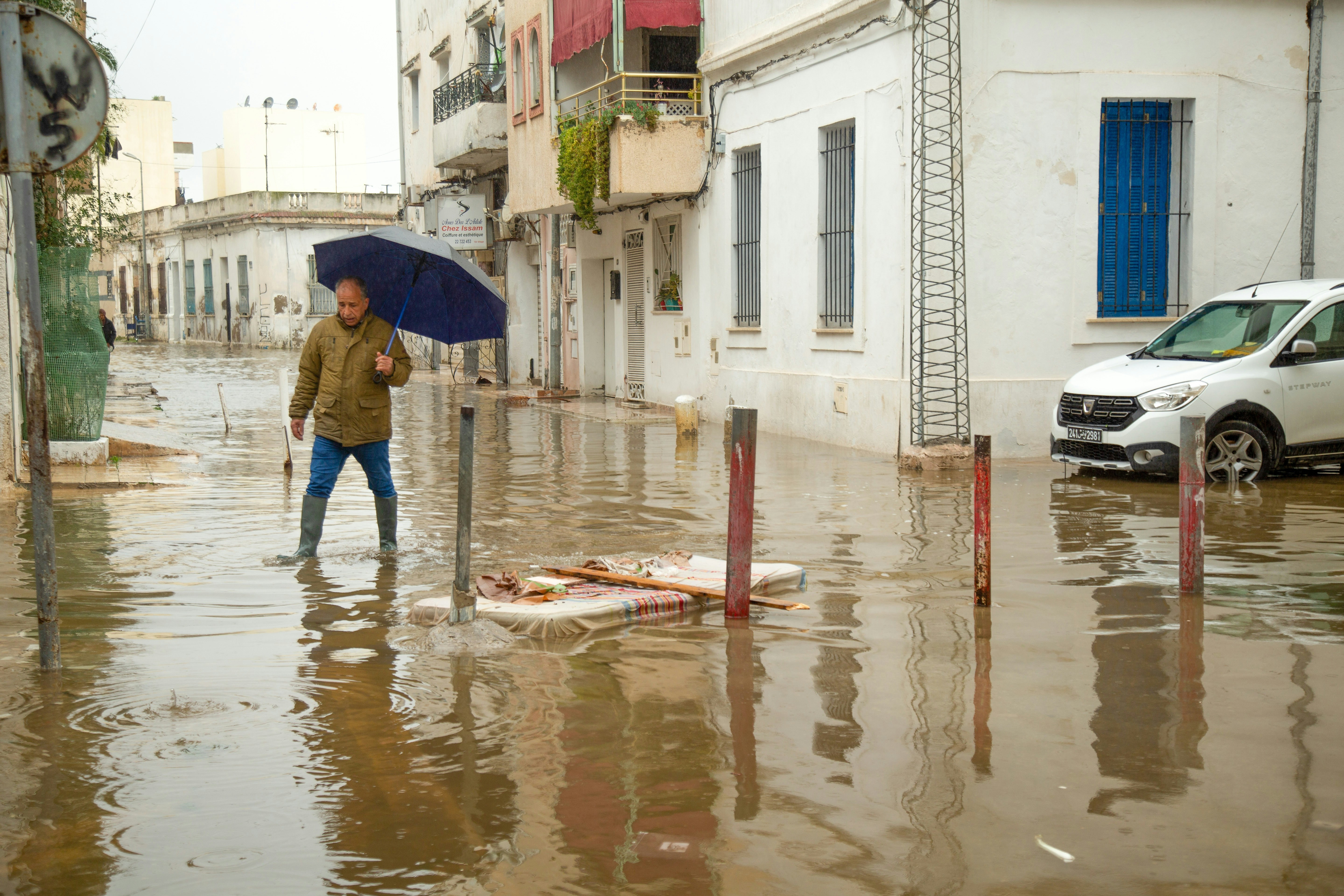 Man walks through flooded street with umbrella