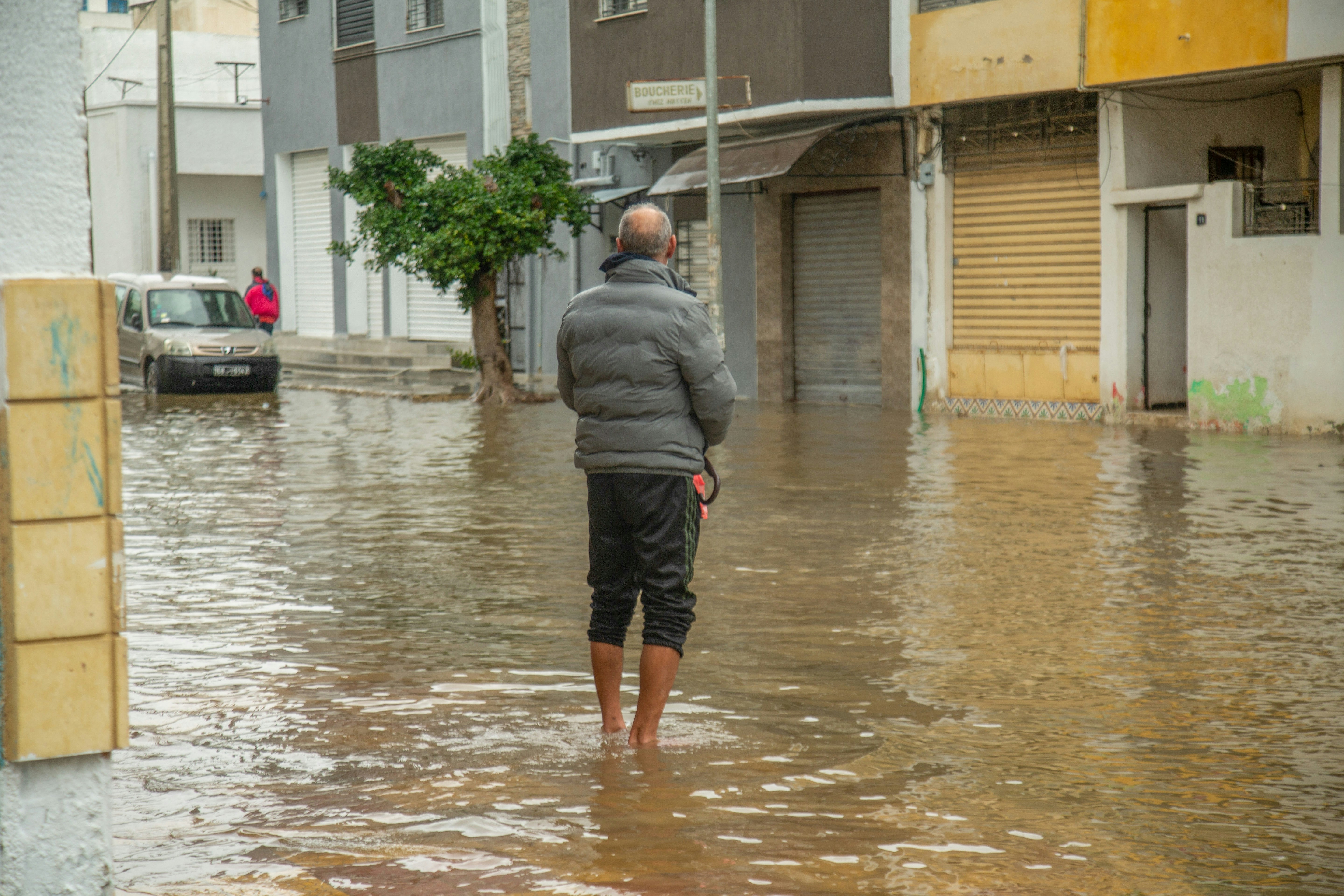 Man stands in flooded street with buildings around