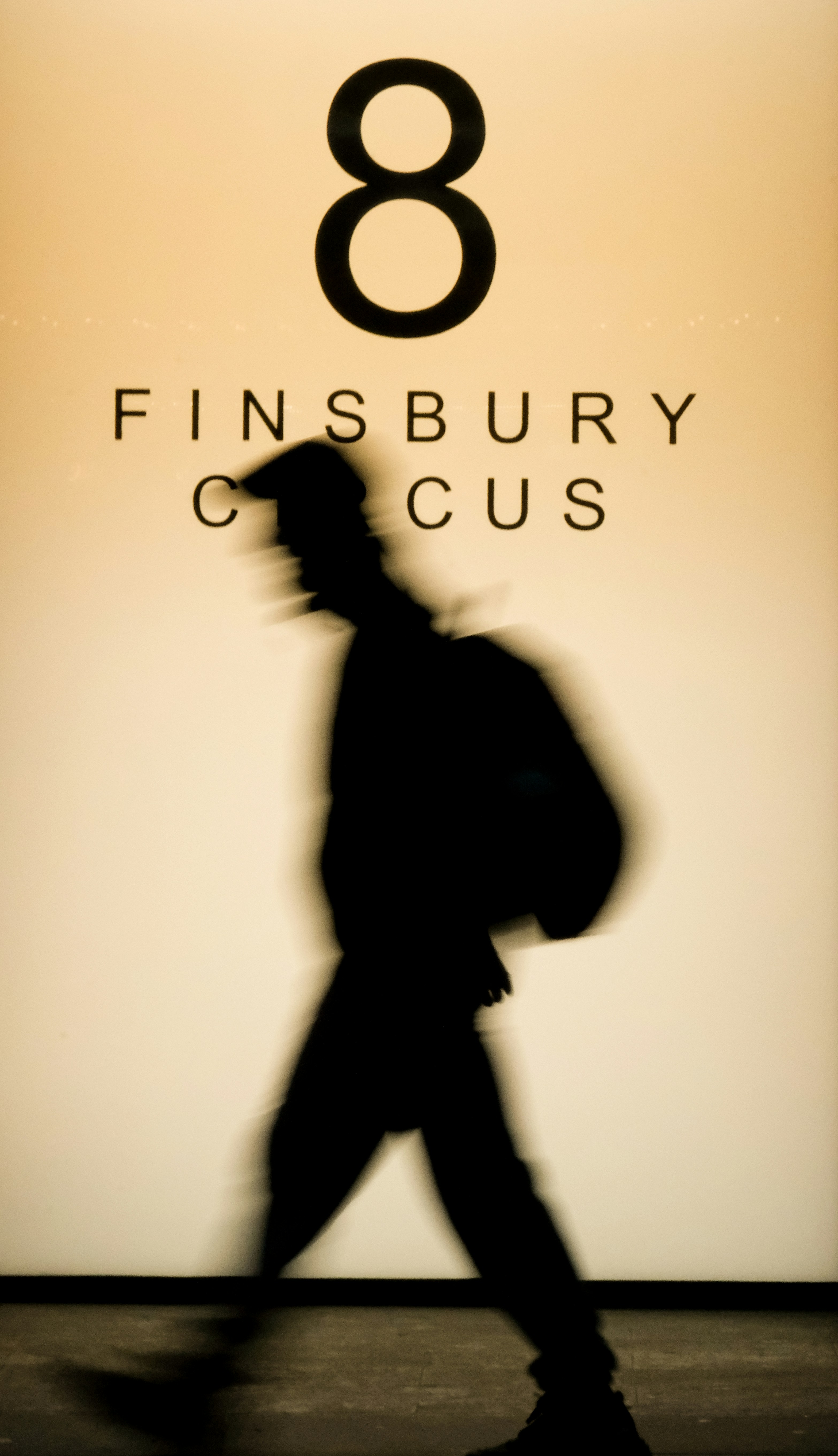 Silhouette of person walking past sign with number eight