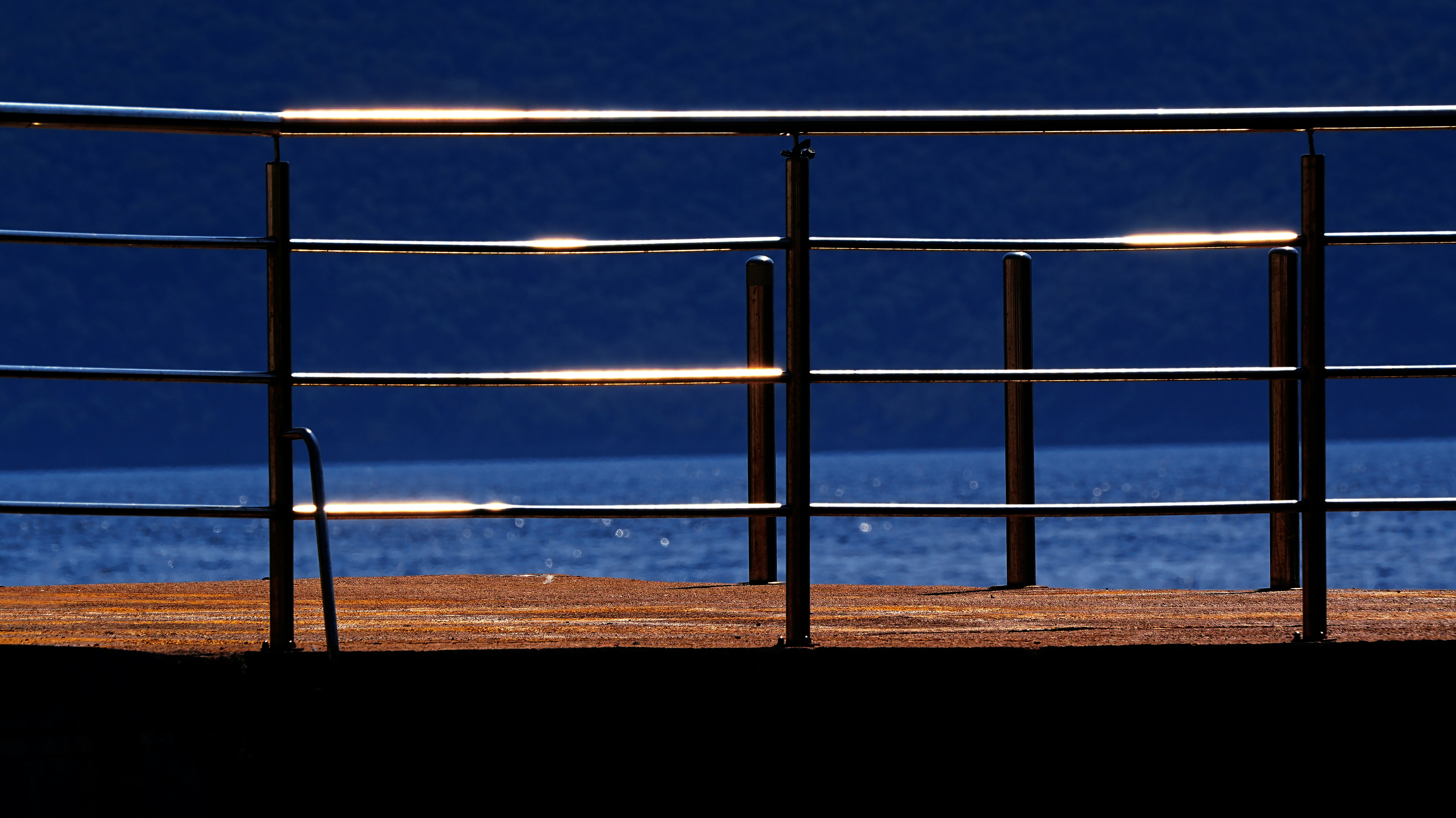 Glänzendes Metallgeländer gegen einen tiefblauen Ozean