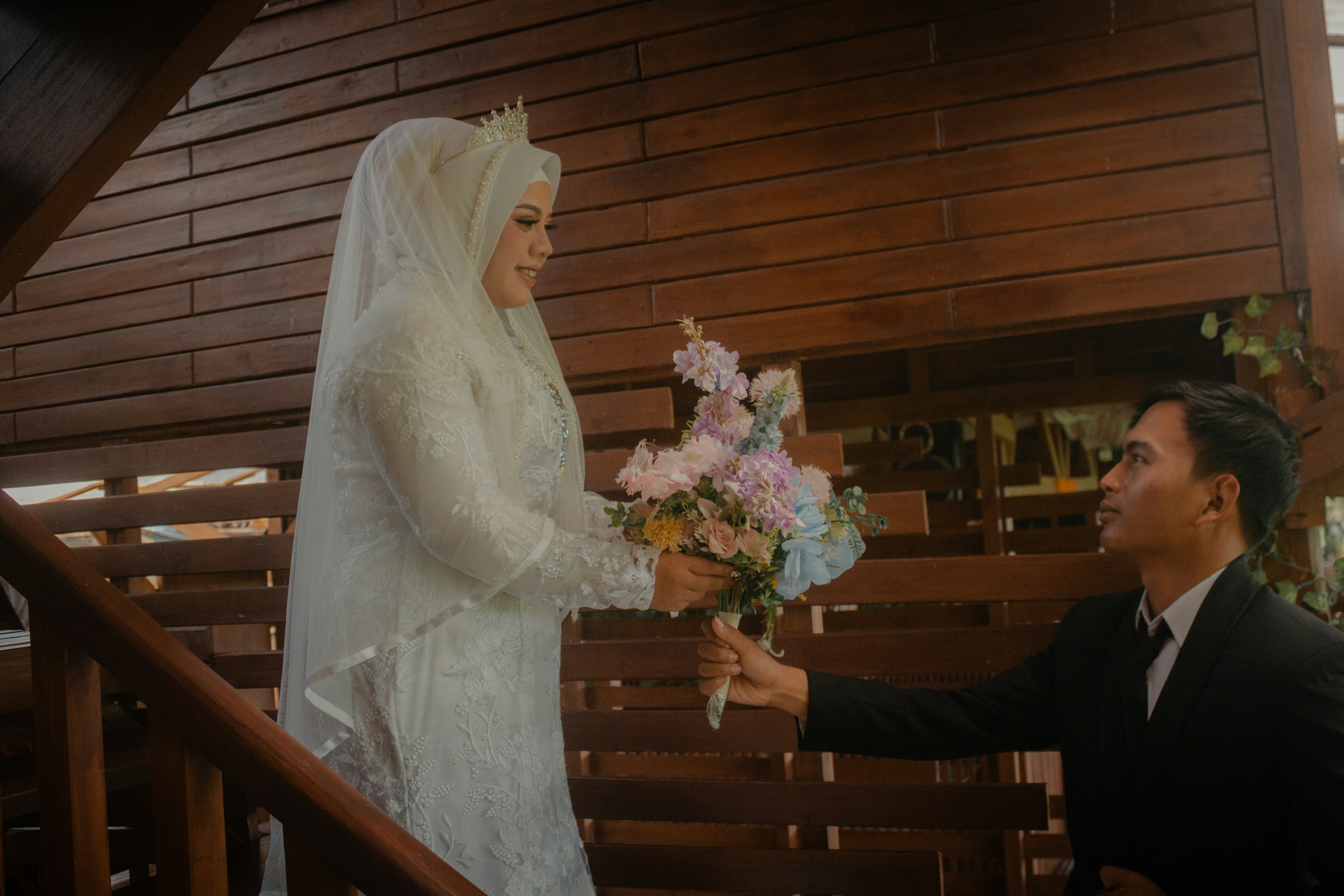 Le marié offre des fleurs à la mariée sur des marches en bois