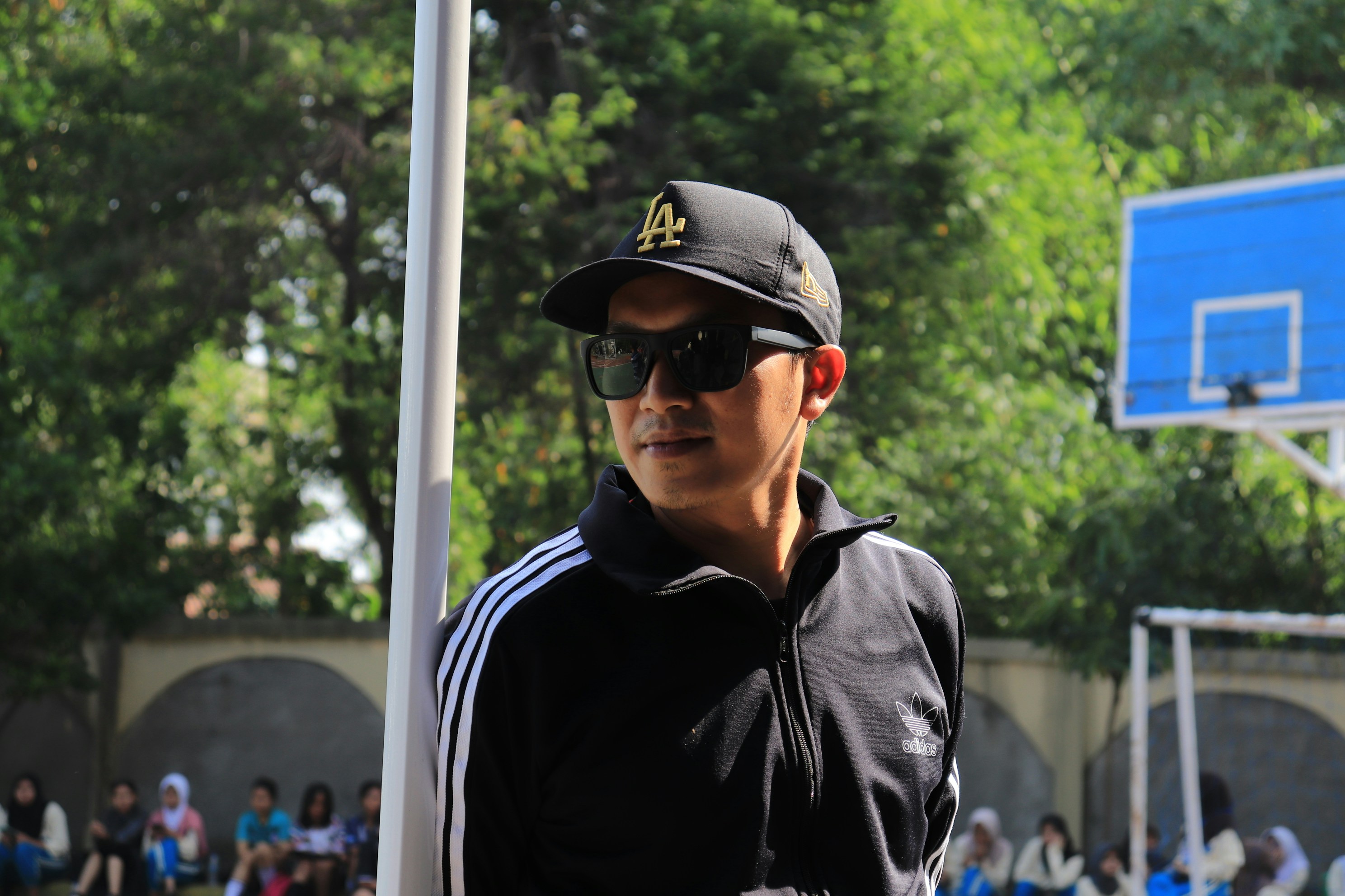 Man in sunglasses and baseball cap on basketball court