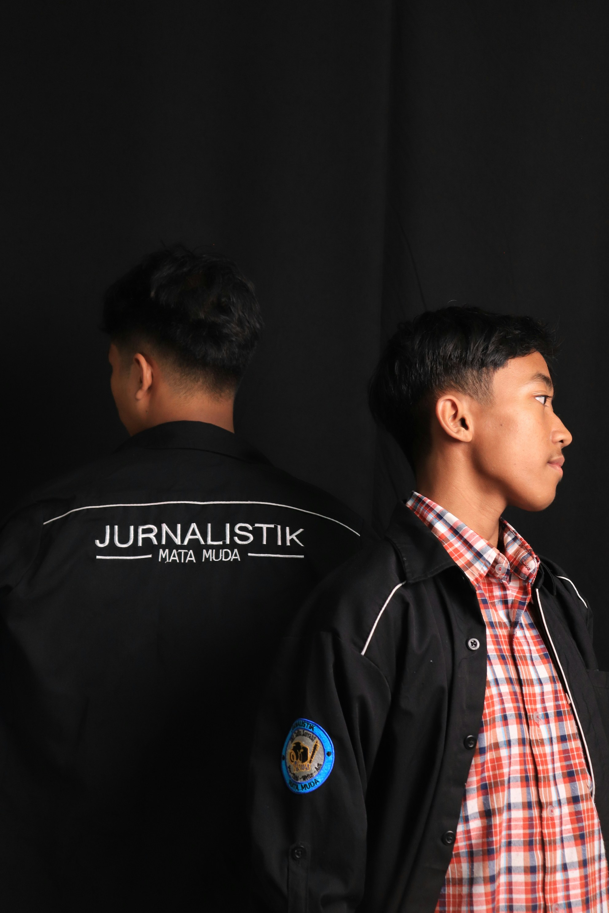 Dua pria muda berjaket dengan latar belakang hitam