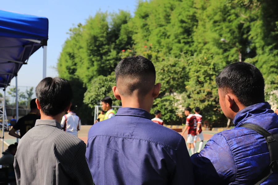 Large crowd watching a football match on a giant outdoor screen at a fan zone