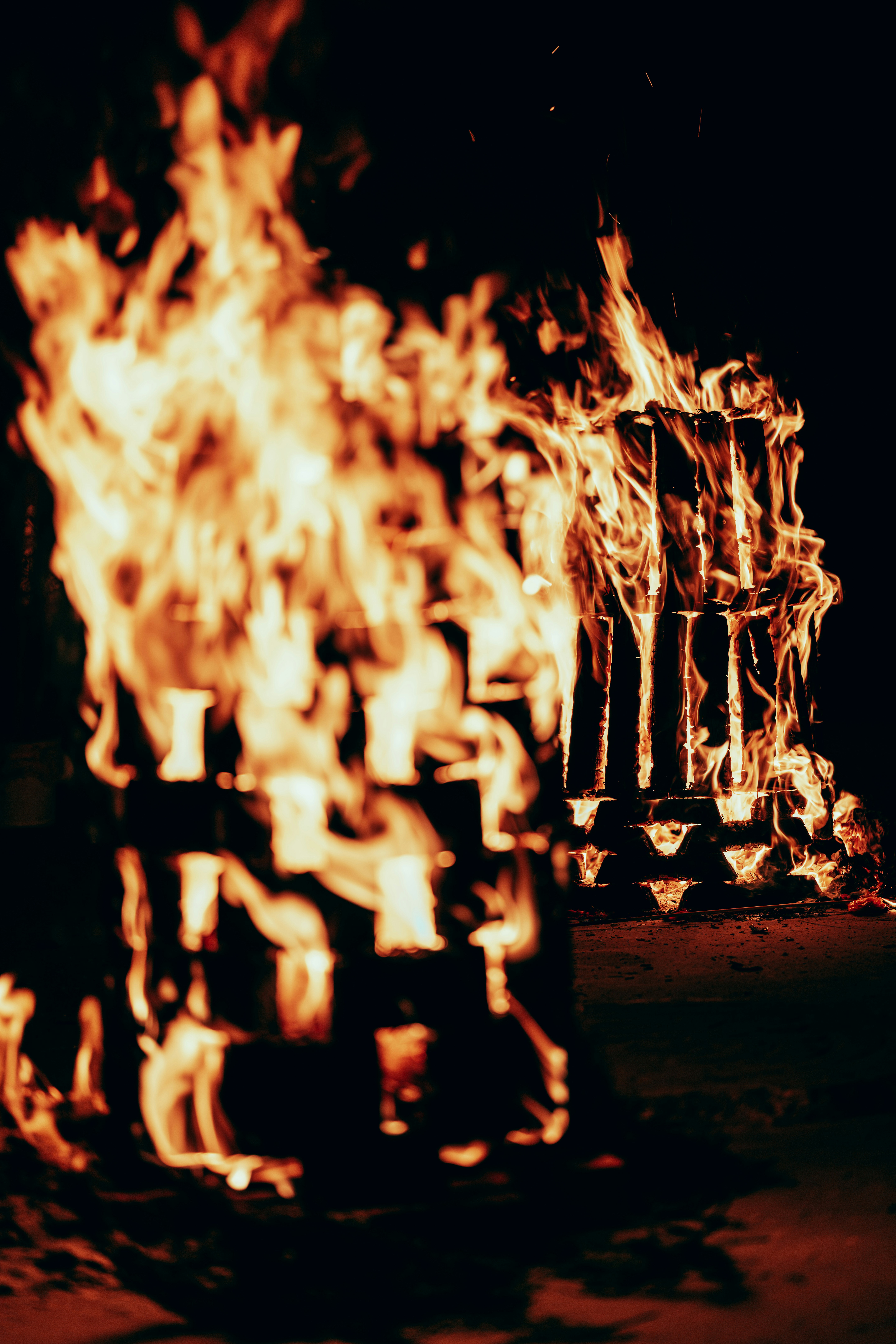 Zwei hölzerne Gebäude, die nachts hell brennen.