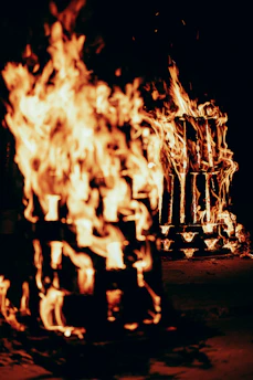 Two wooden structures burning brightly at night