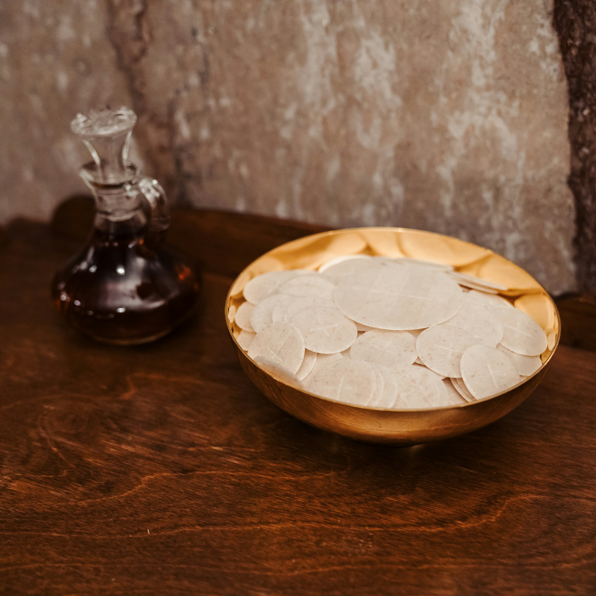 A golden bowl of communion wafers and a small decanter