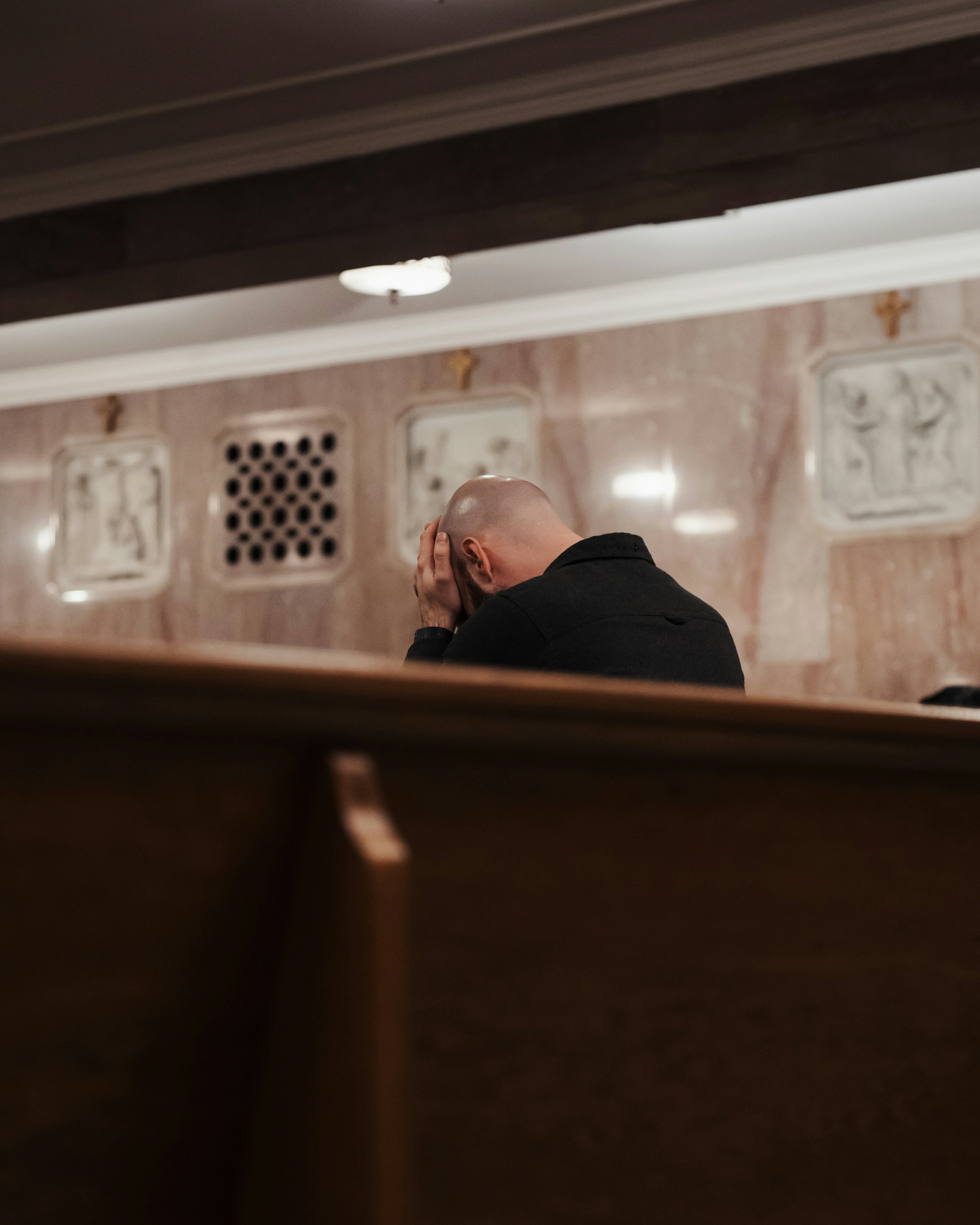 Man bowing head in prayer inside a church