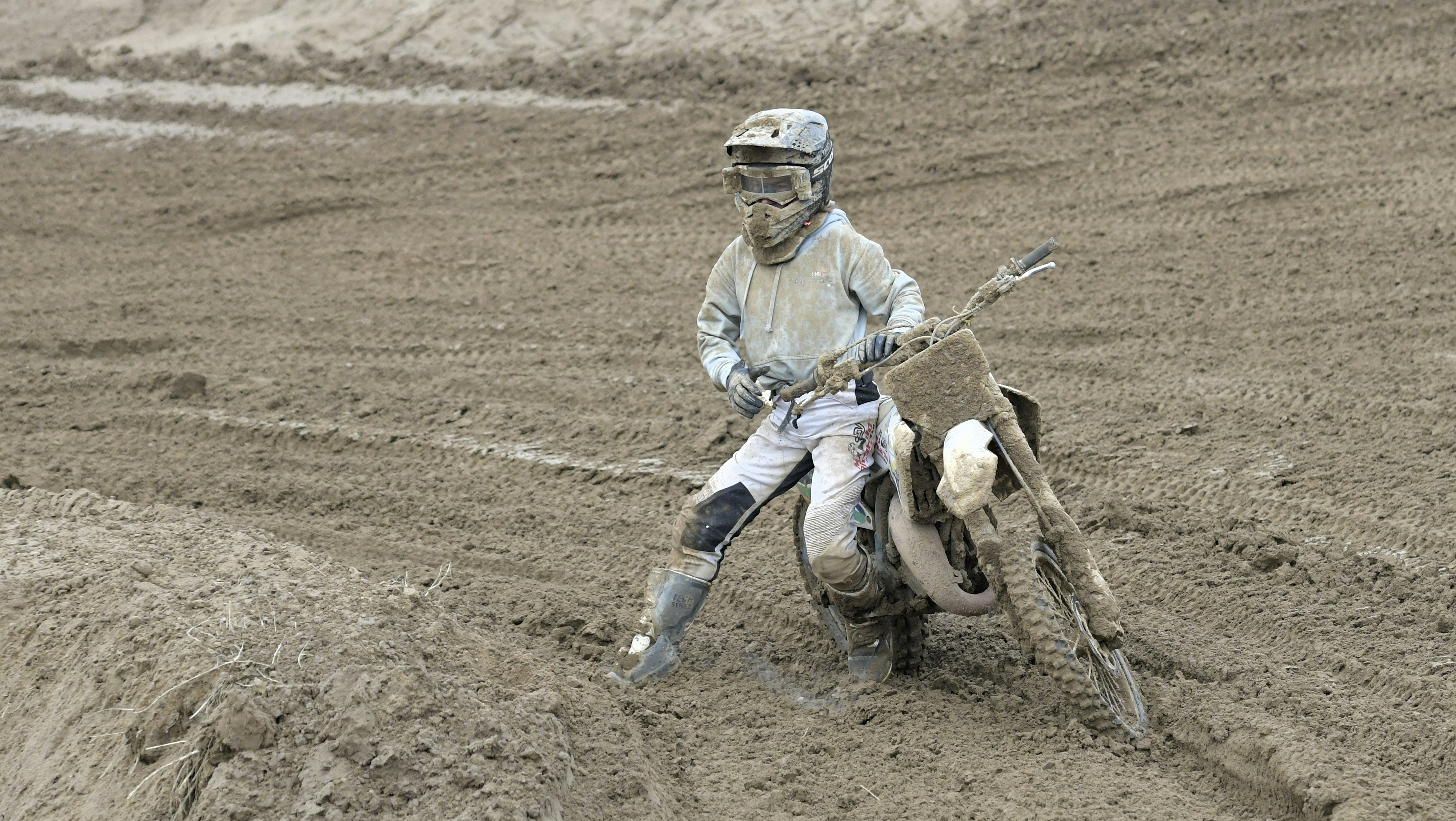 Motocross rider covered in mud on a dirt track