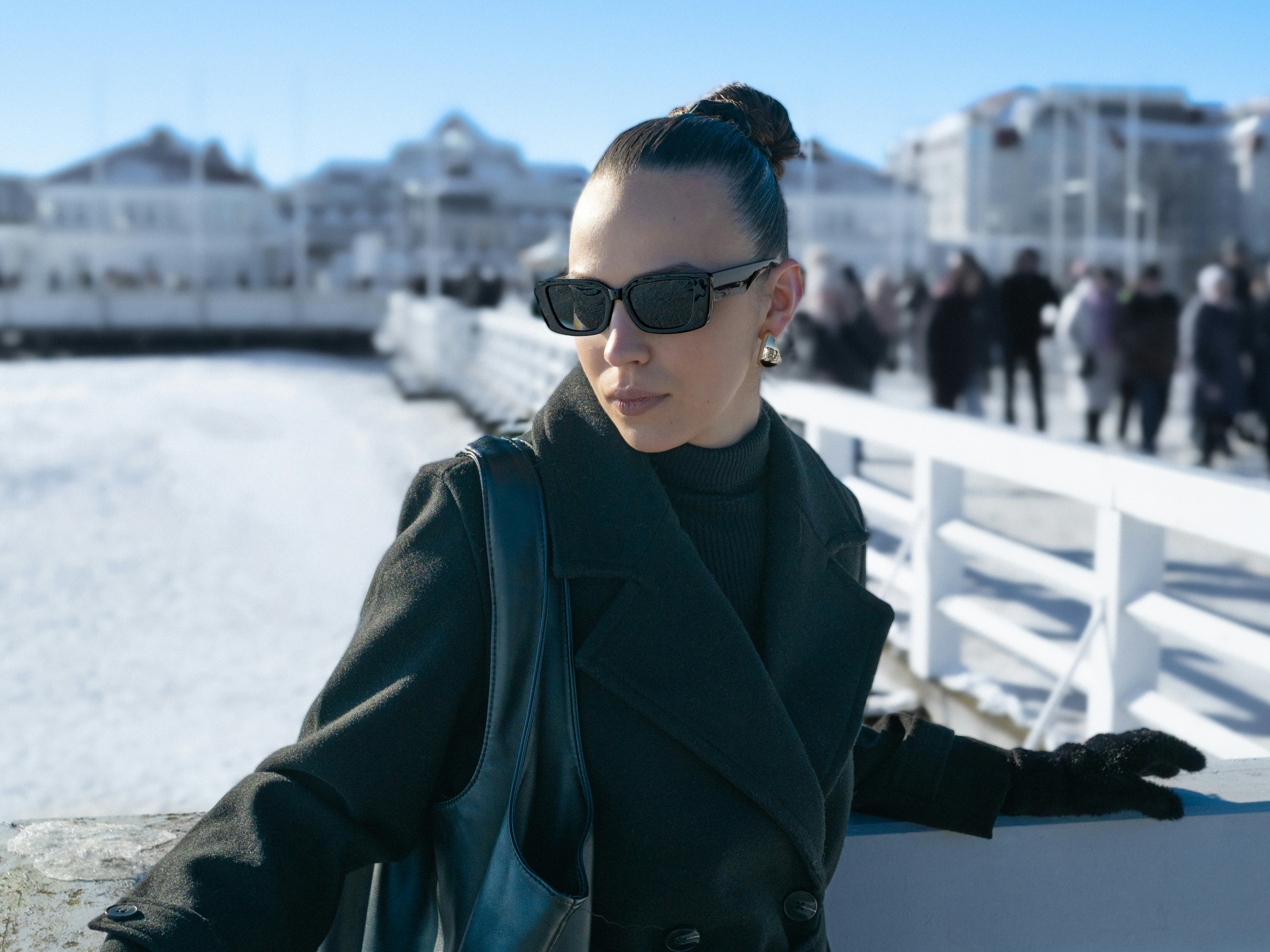 Femme en lunettes de soleil et manteau par une journée d’hiver ensoleillée