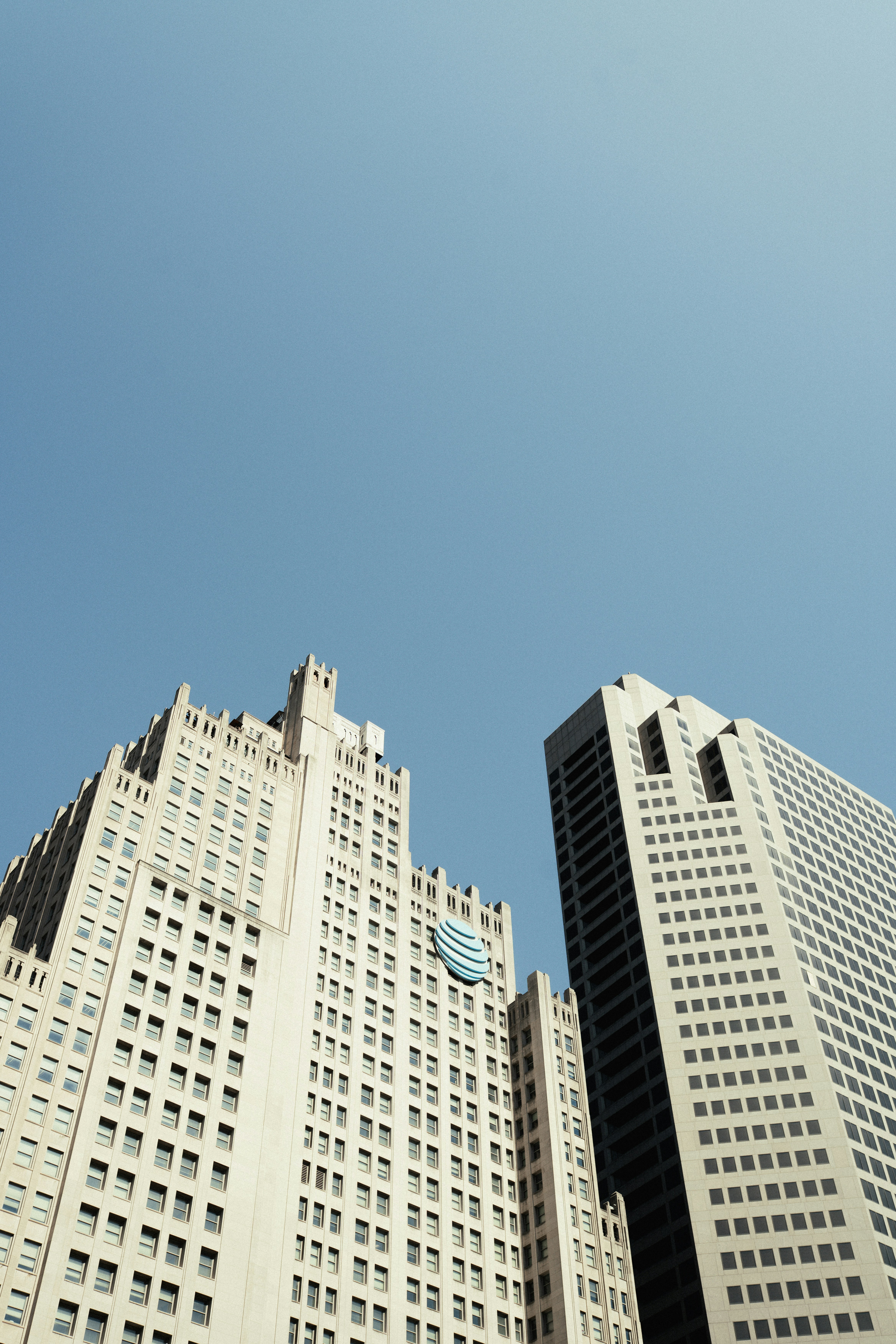 Two modern skyscrapers against a clear blue sky
