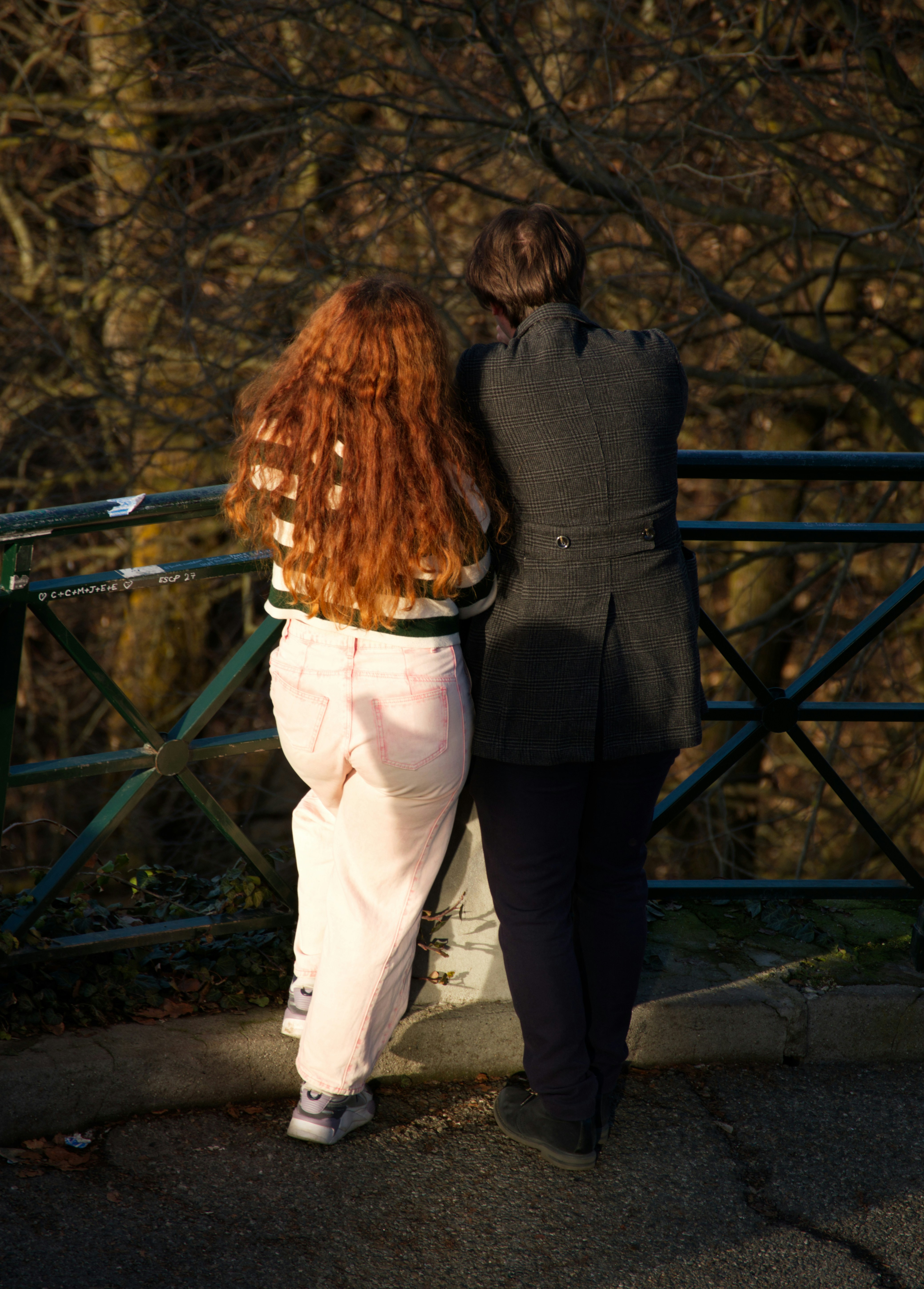 Due persone in piedi vicino a una ringhiera, distogliendo lo sguardo