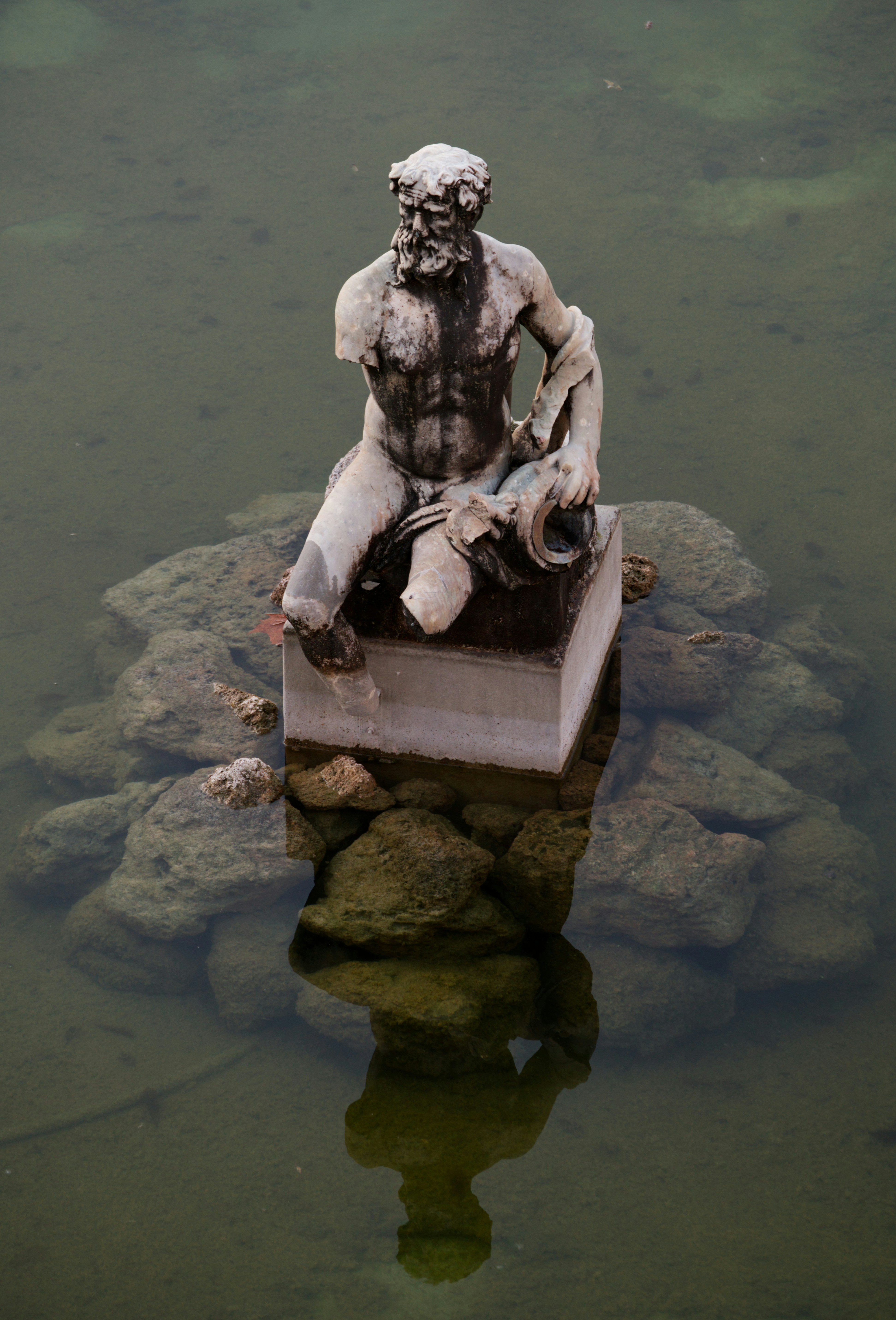 Antica statua di un uomo seduto nell'acqua
