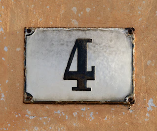 A weathered house number 4 on a textured wall.