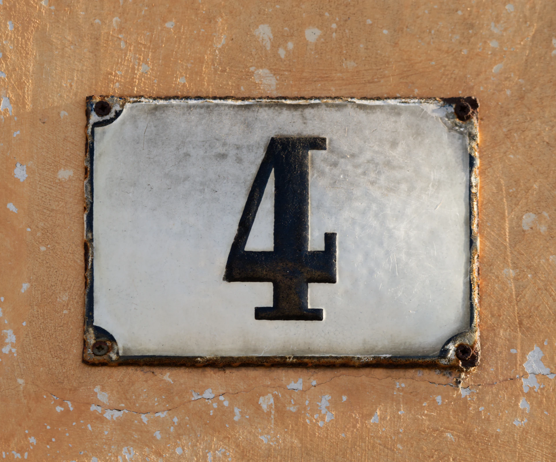 A weathered house number 4 on a textured wall.