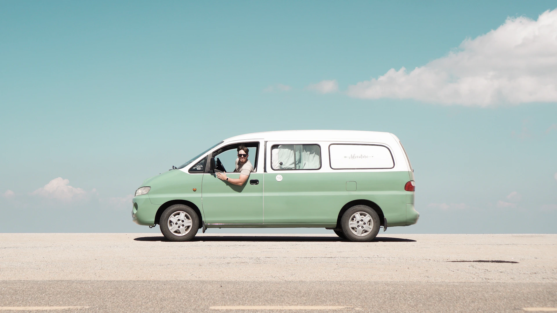 Man driving a mint green van on a sunny day