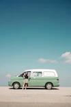 Woman standing by a vintage green camper van