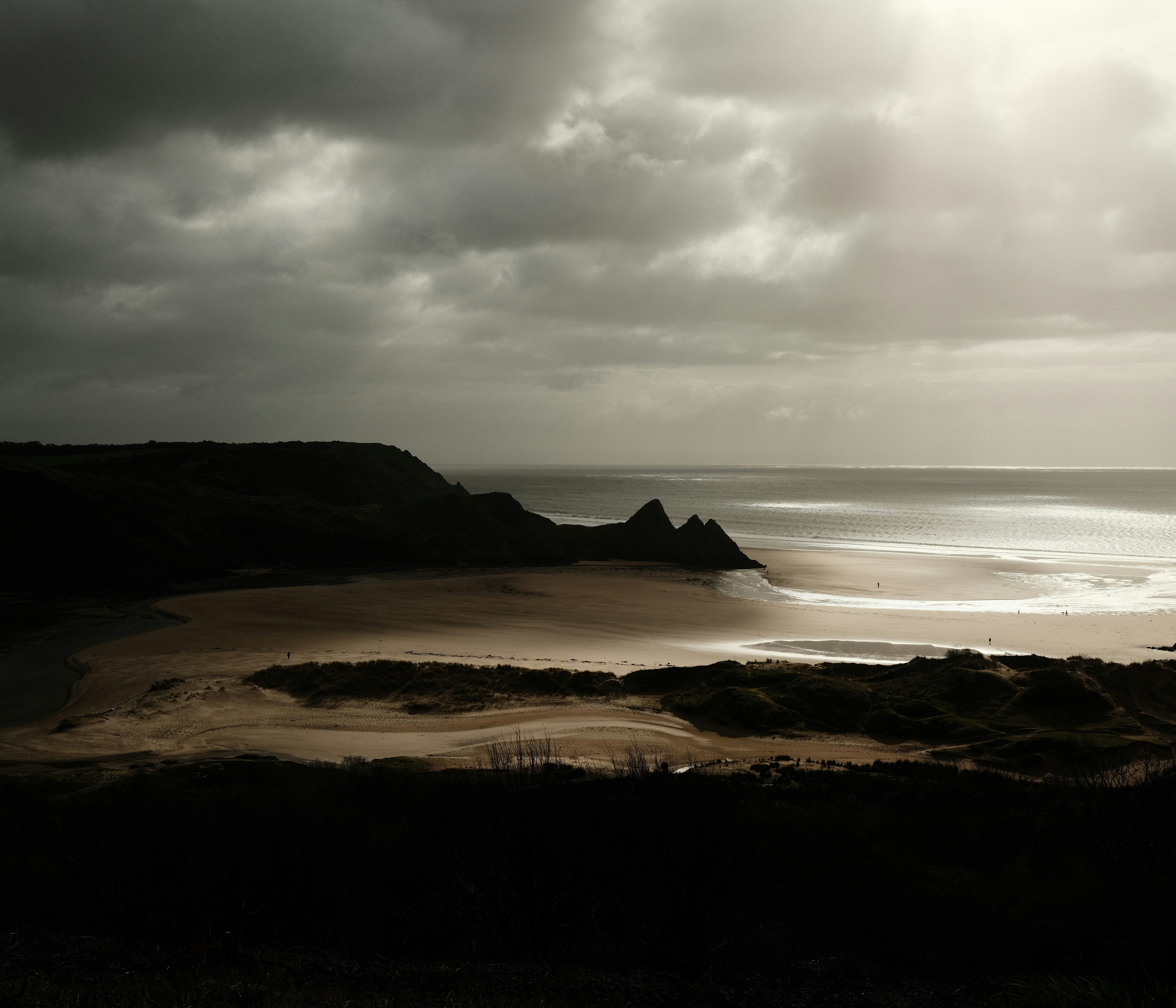 Dramatic cloudy sky over a serene beach landscape.