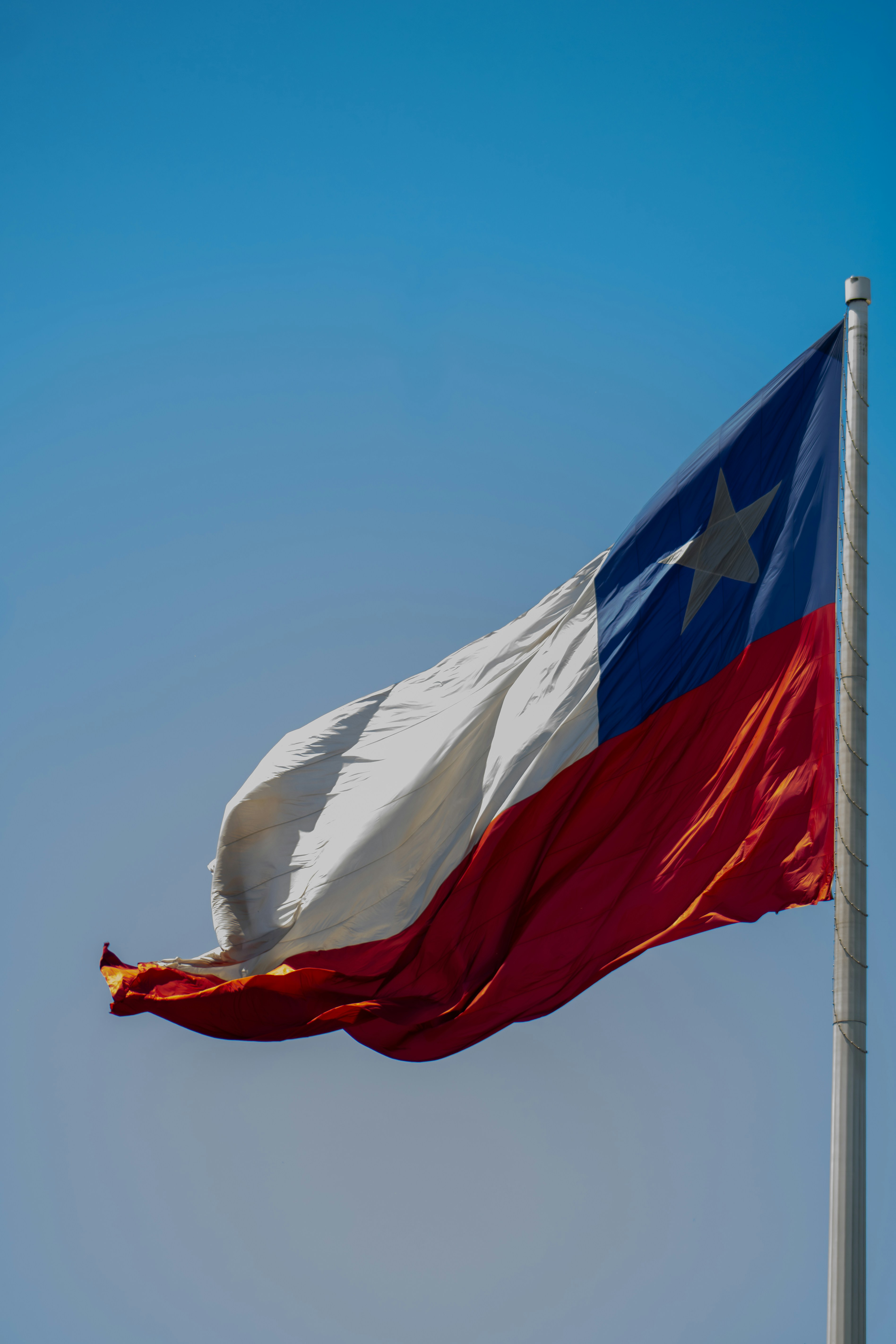 La bandera chilena ondea contra un cielo azul despejado.