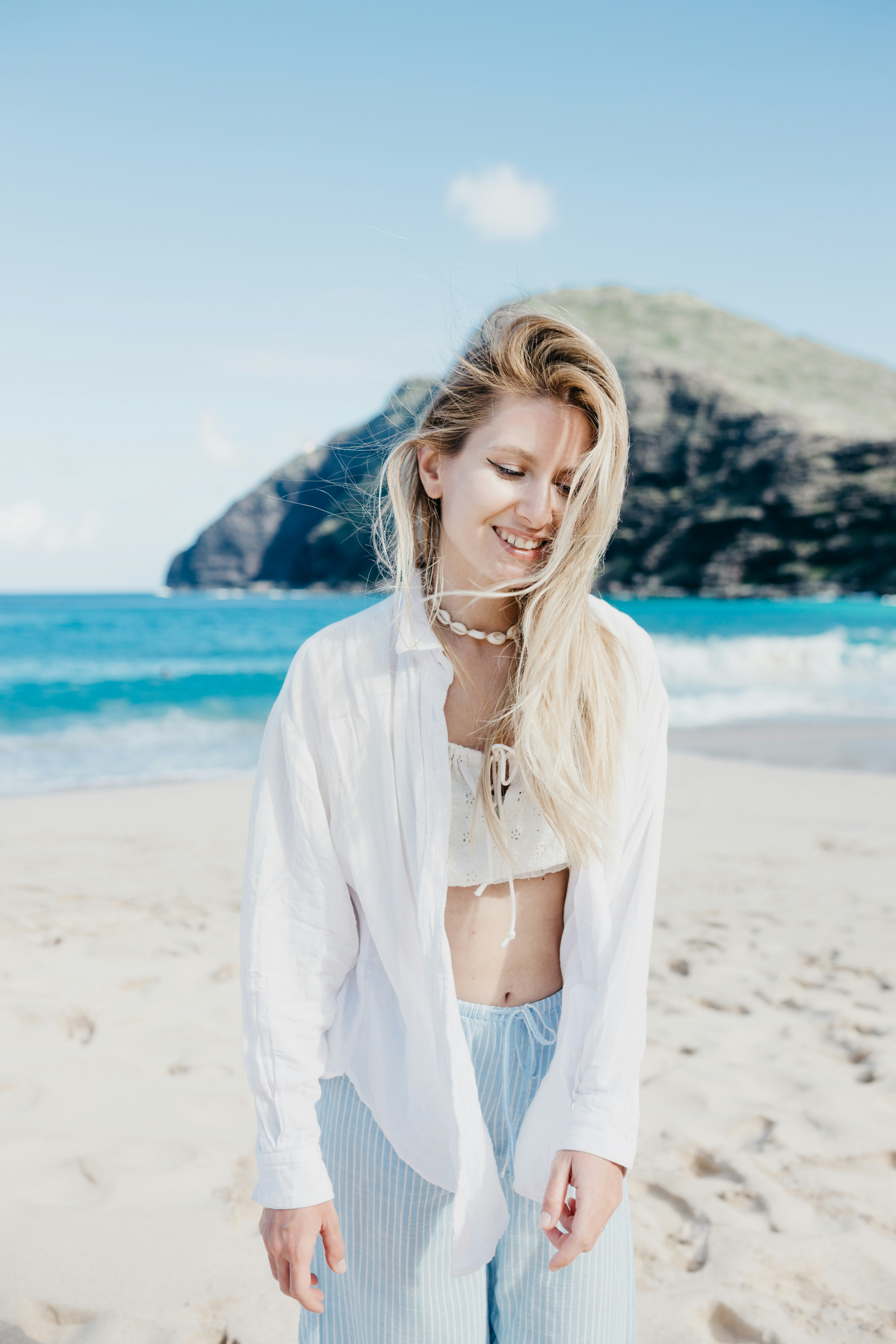 Jeune femme souriante sur une plage ensoleillée avec un fond océanique