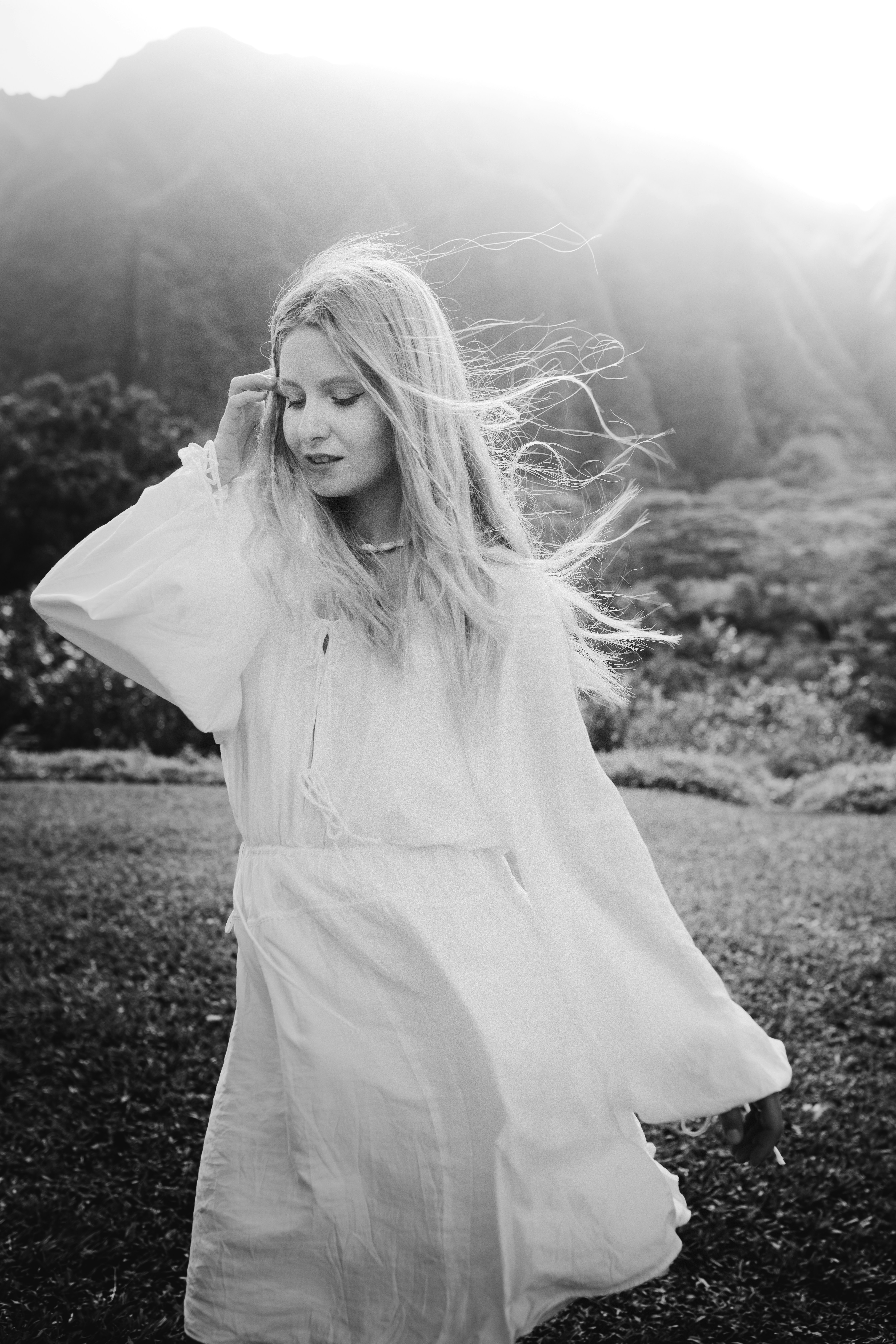 Une femme en robe blanche aux cheveux ébouriffés par le vent dehors