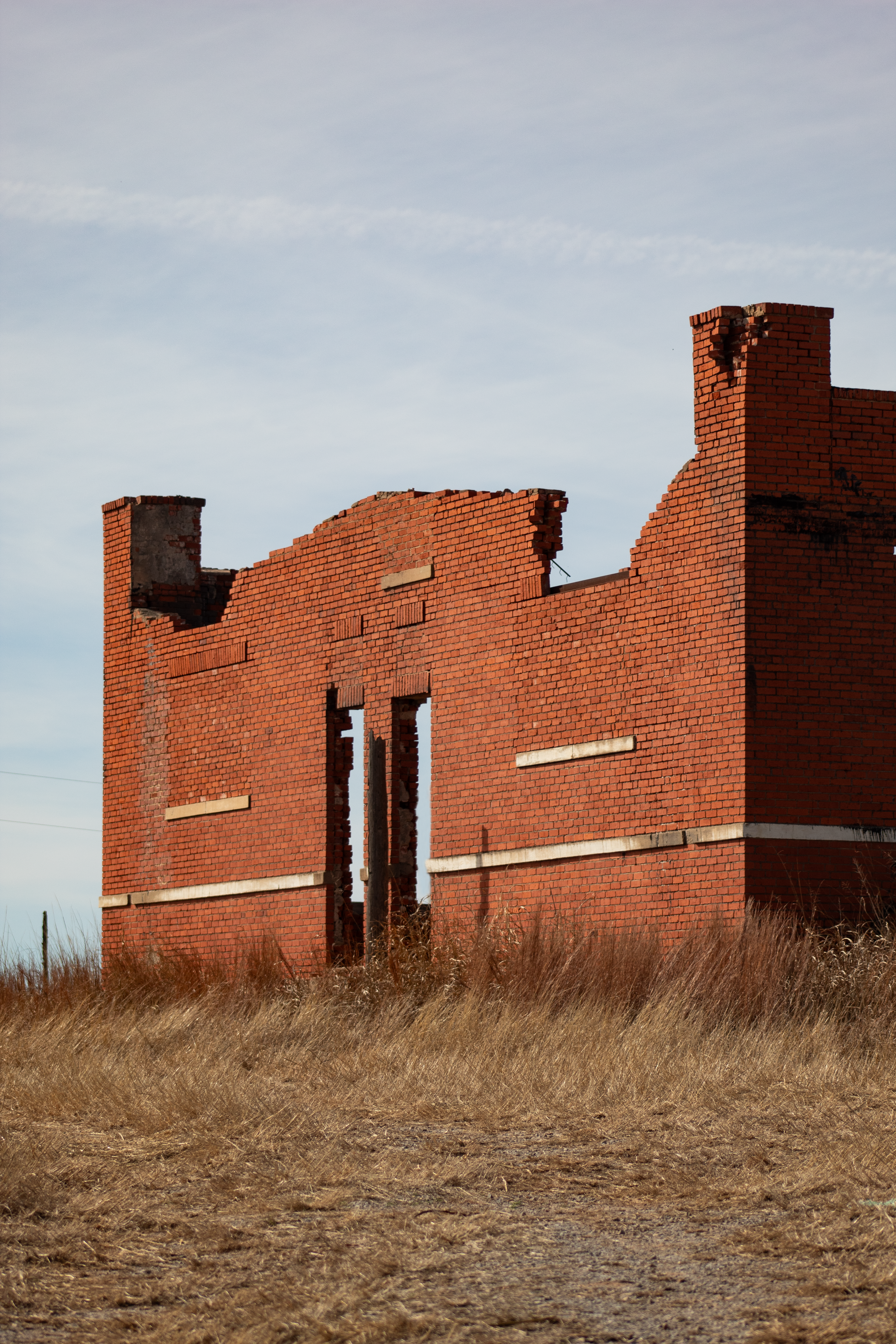 Bâtiment en briques en ruines se dresse dans l’herbe sèche sous le ciel