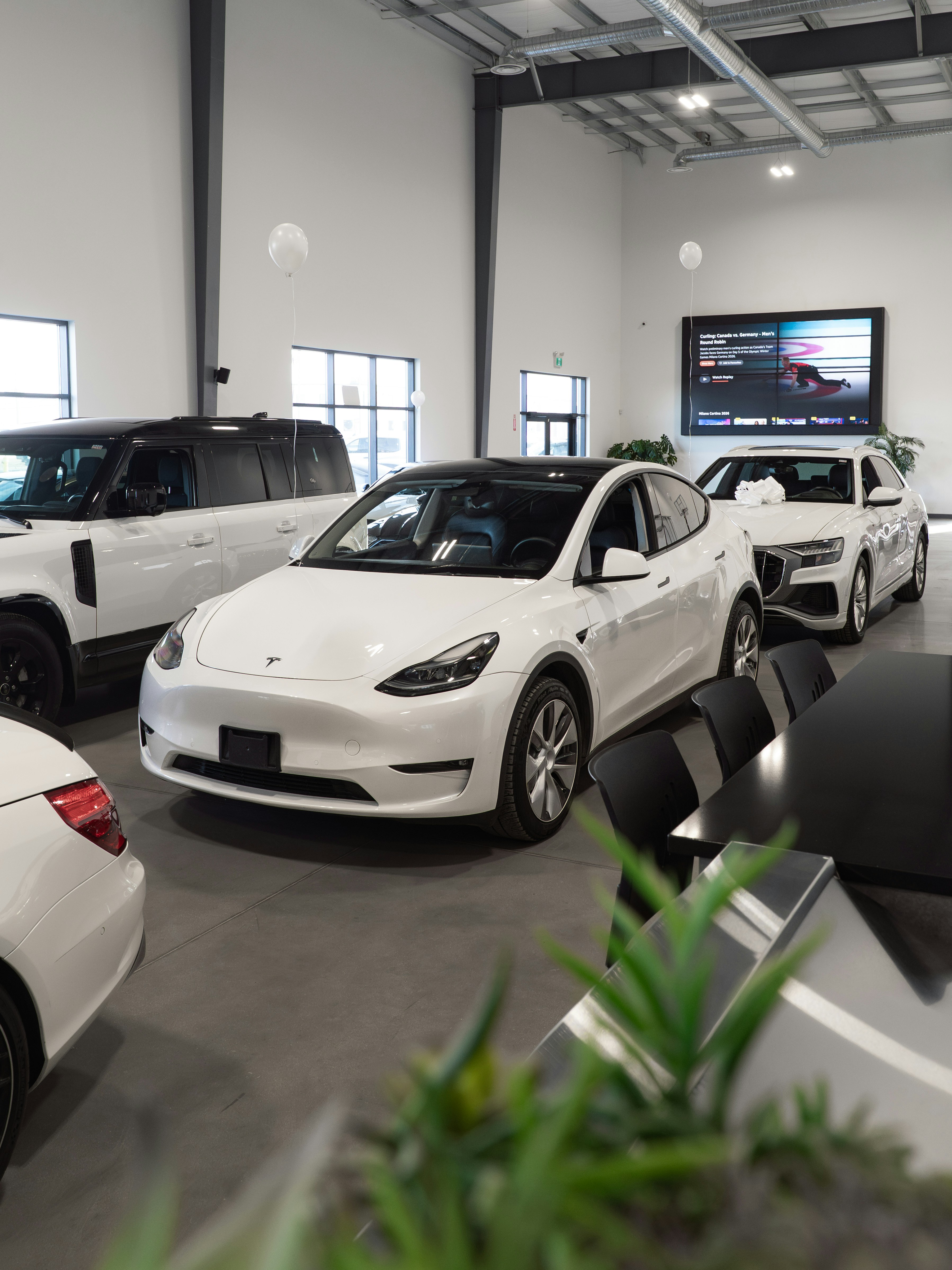 White tesla model y parked inside a showroom.