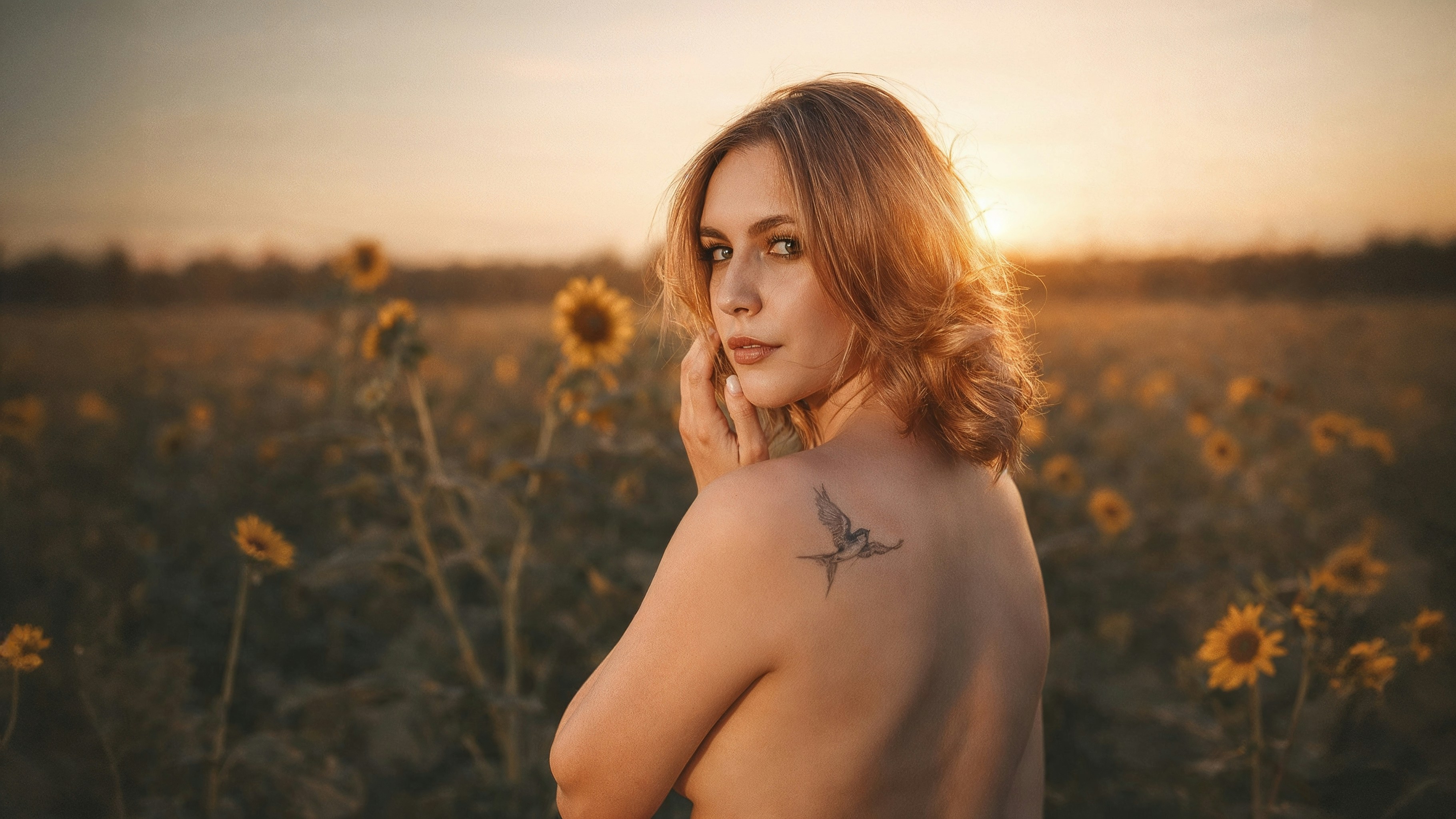 Woman in sunflower field at sunset