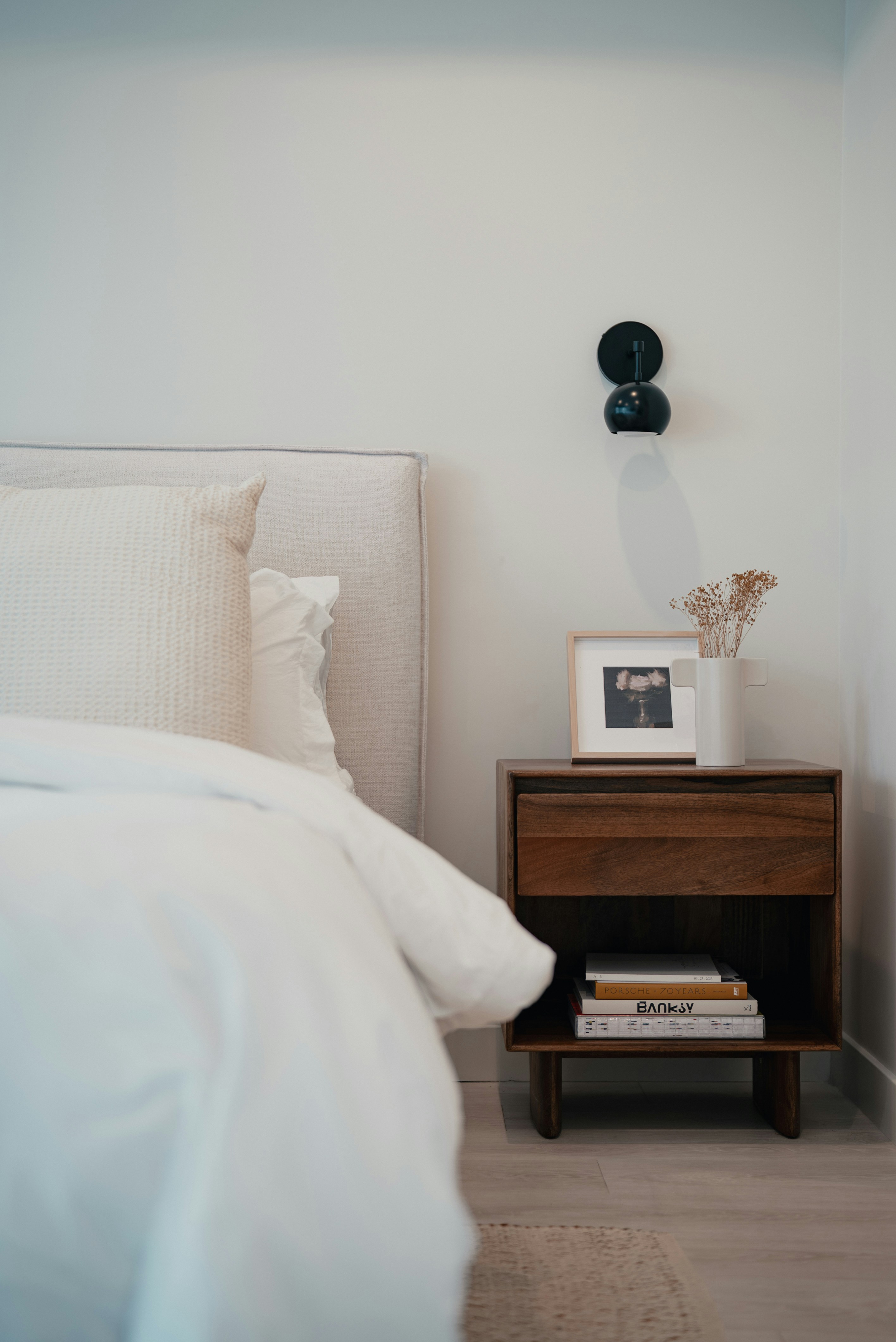 Moderner Nachttisch mit Büchern und gerahmter Kunst.