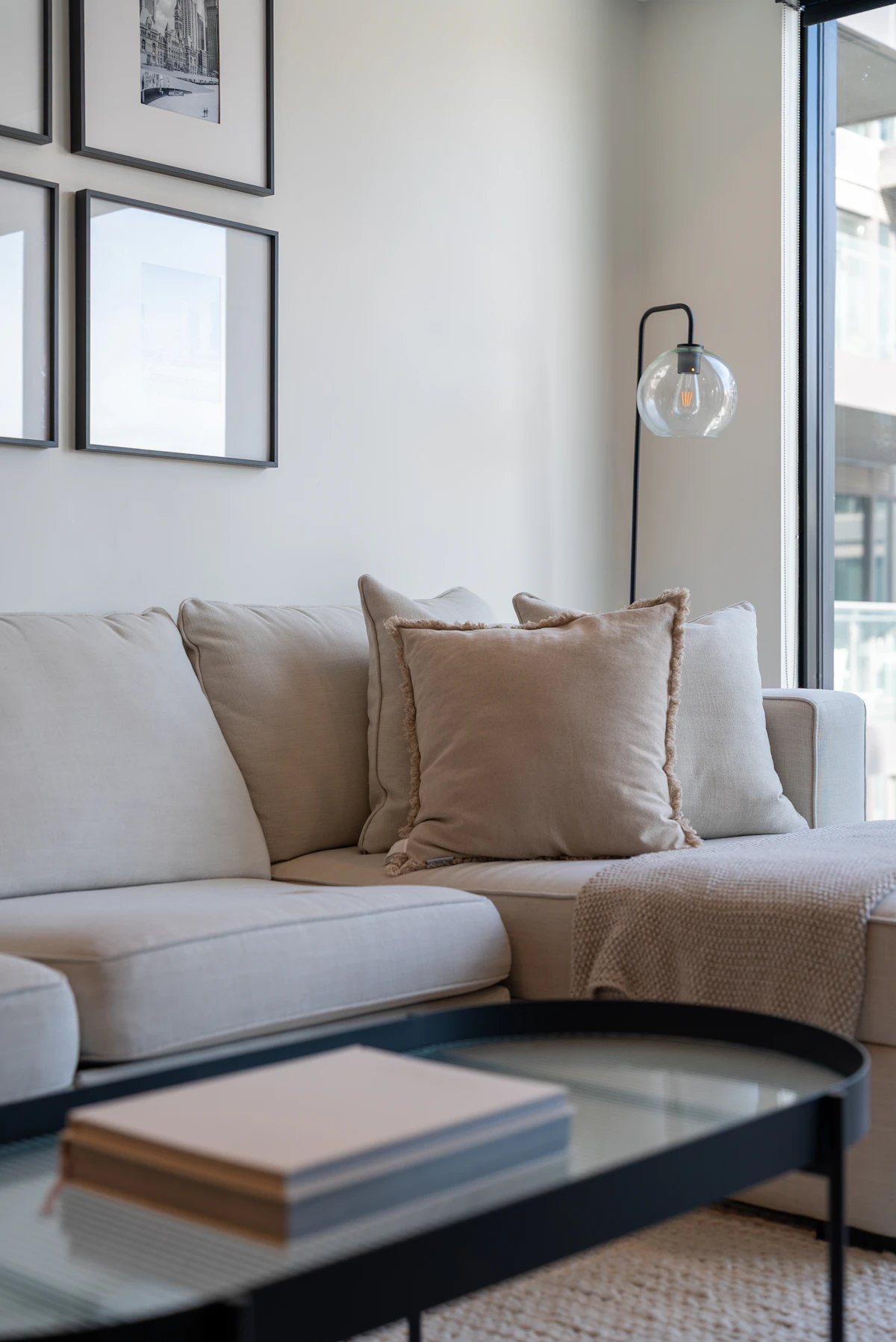 Beige sofa with linen cushions beside a glass coffee table