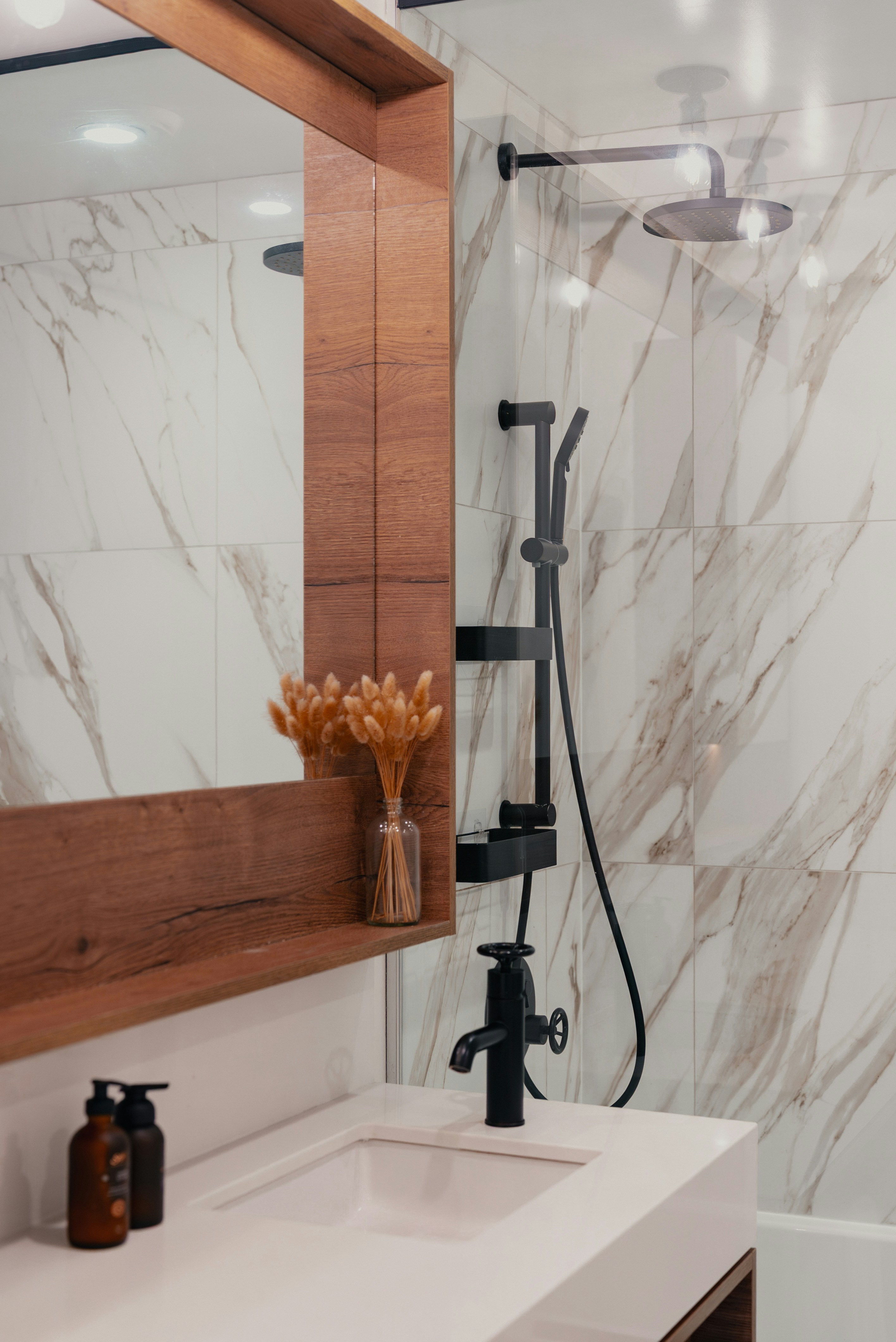 Modernes Badezimmer mit Marmorfliesen und schwarzen Armaturen.