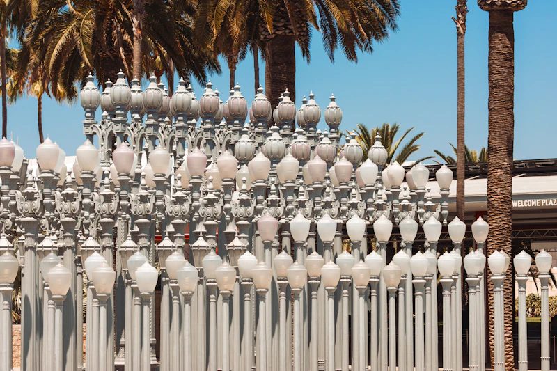 Rows of vintage streetlamps with palm trees behind