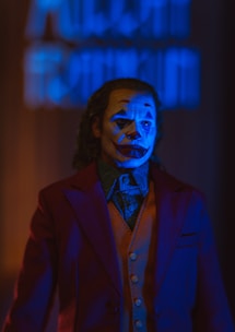 Man with clown makeup and suit in blue light