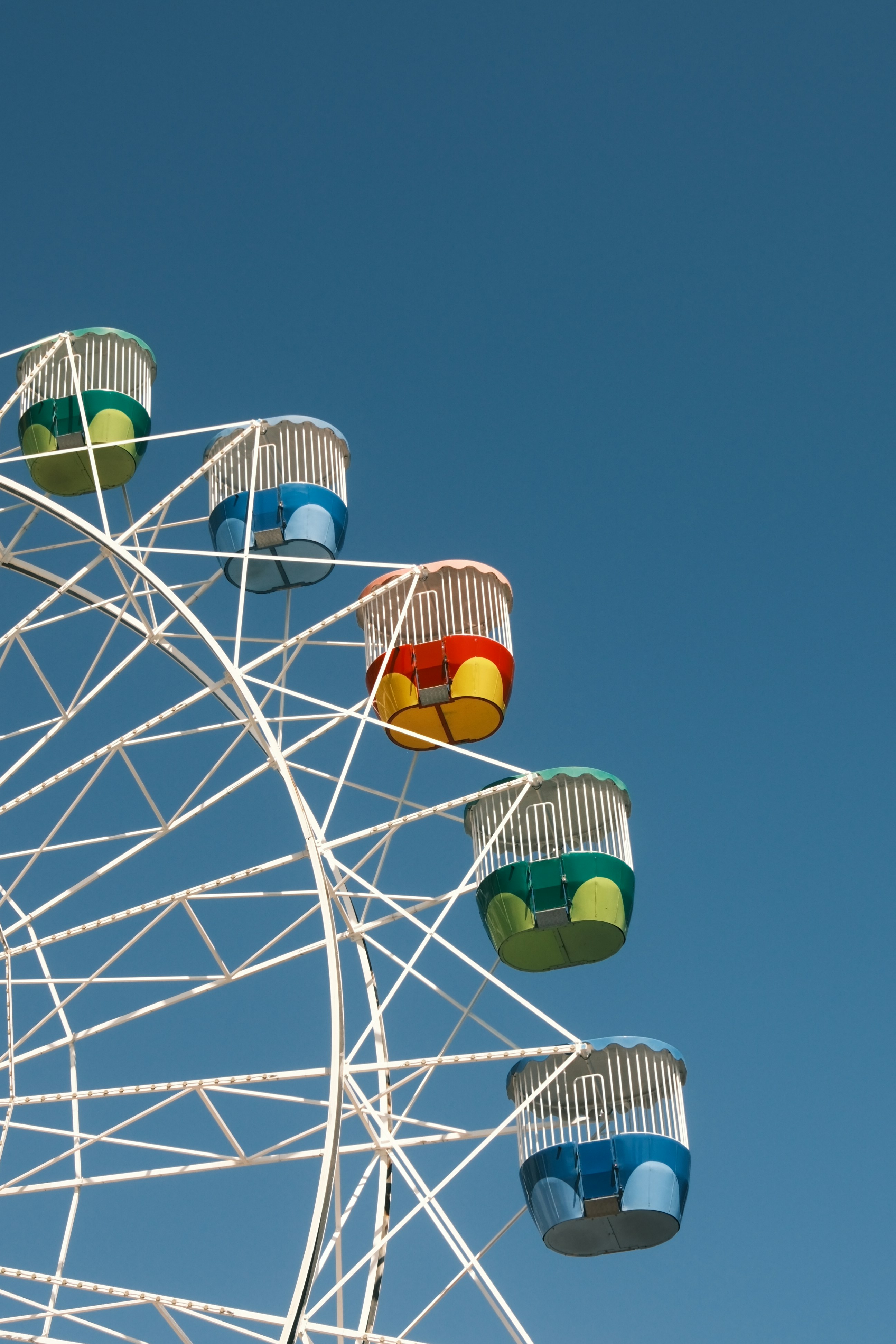 Colorful ferris wheel cabins against a clear blue sky