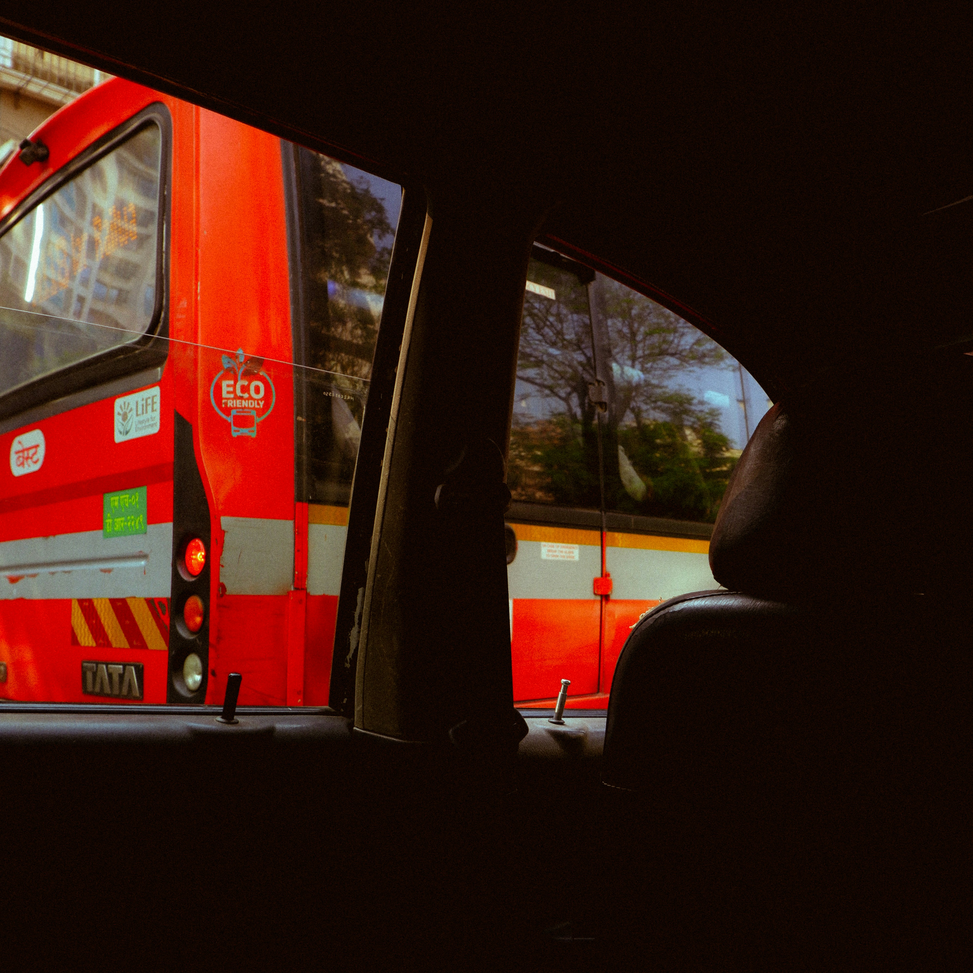 Red bus seen from inside a car window