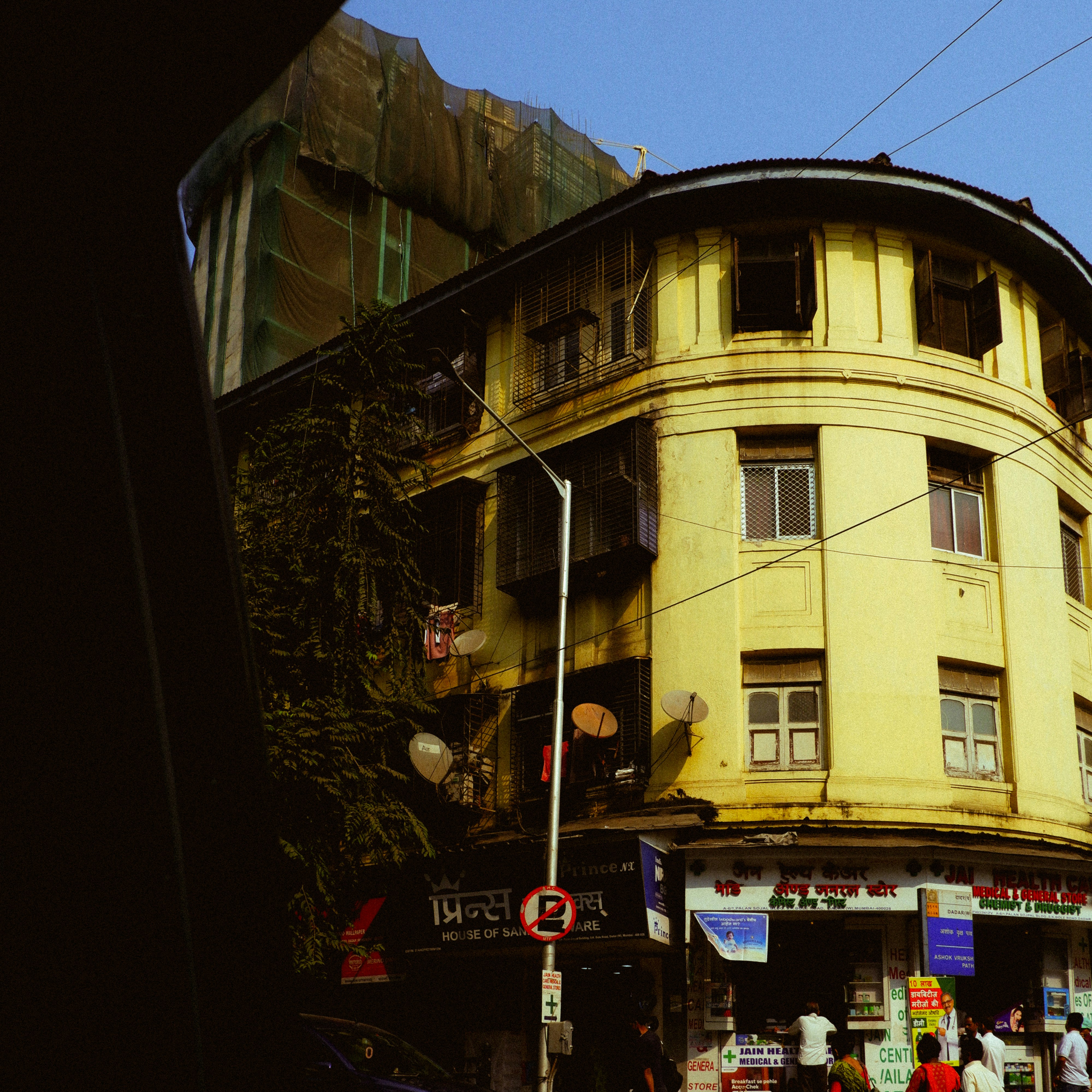 A yellow building with shops on the ground floor.