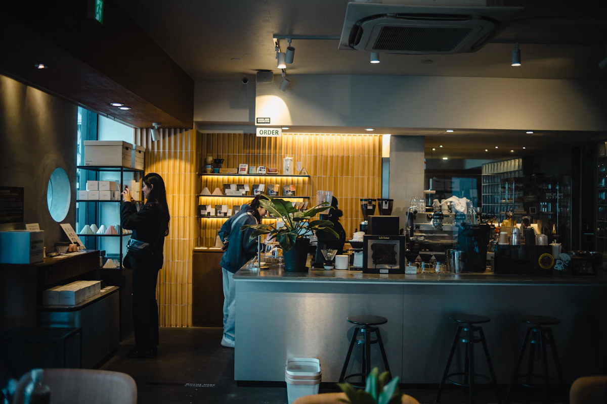 People at the cafe counter with baked goods on display